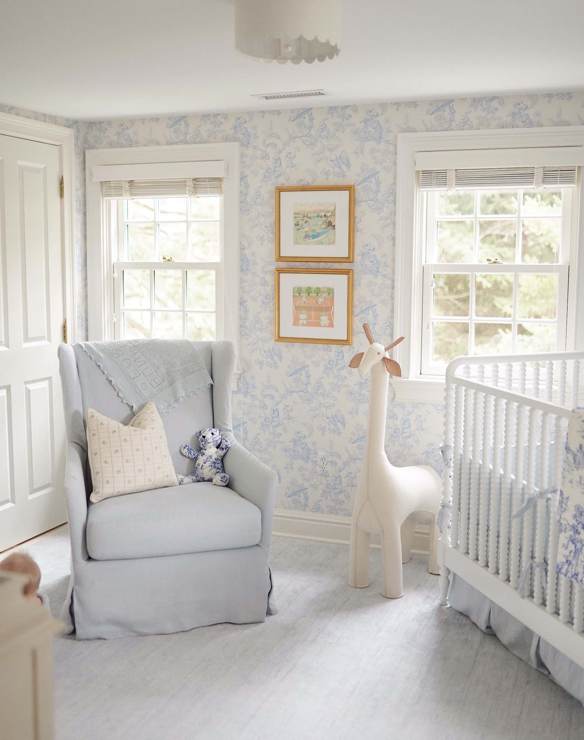 Nursery 桌布 壁紙 — 寧靜的嬰兒房，配有淺藍色 toile 牆紙、白色嬰兒床和扶手椅，窗戶透入自然光。
