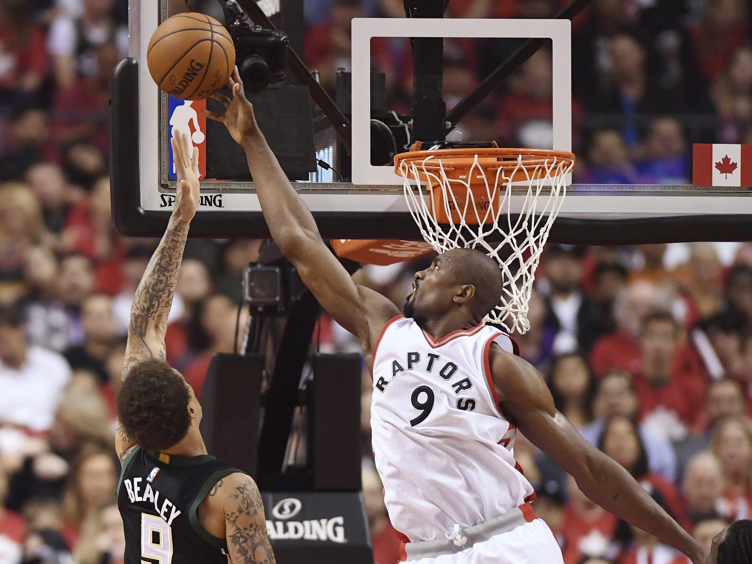 Serge Ibaka 阻擋 Beasley 壁紙 — 多倫多速龍隊身穿白色球衣9號的球員灌籃，而綠色球衣的防守球員試圖封阻。