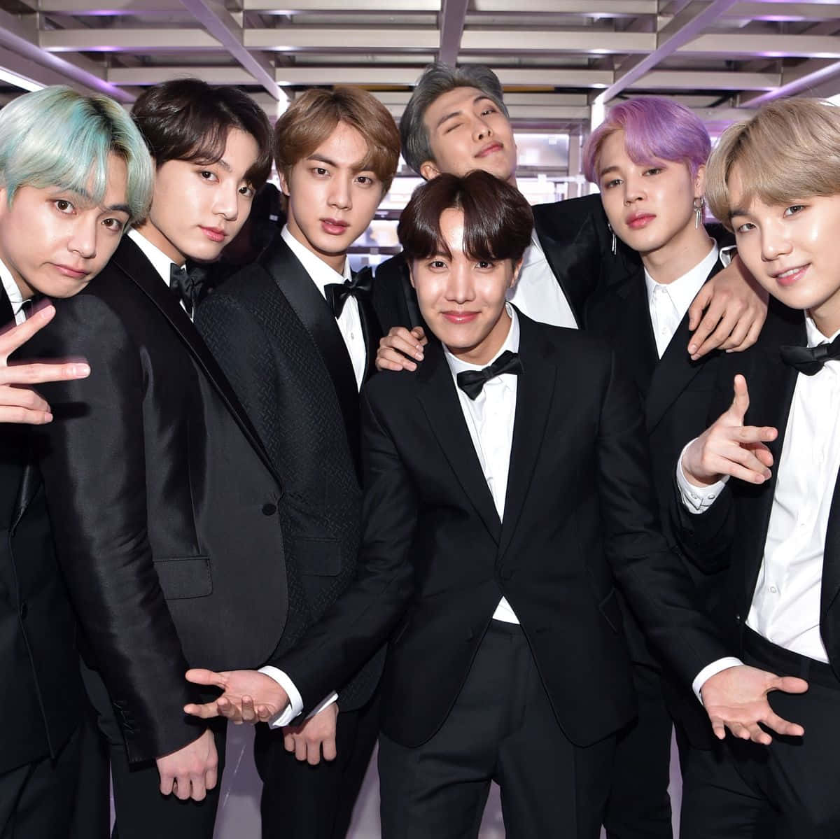 BTS 2021 格萊美獎後台照 壁紙 — 七位身穿黑色禮服、頭髮色彩繽紛的男士在紫色燈光下自信地擺姿勢。