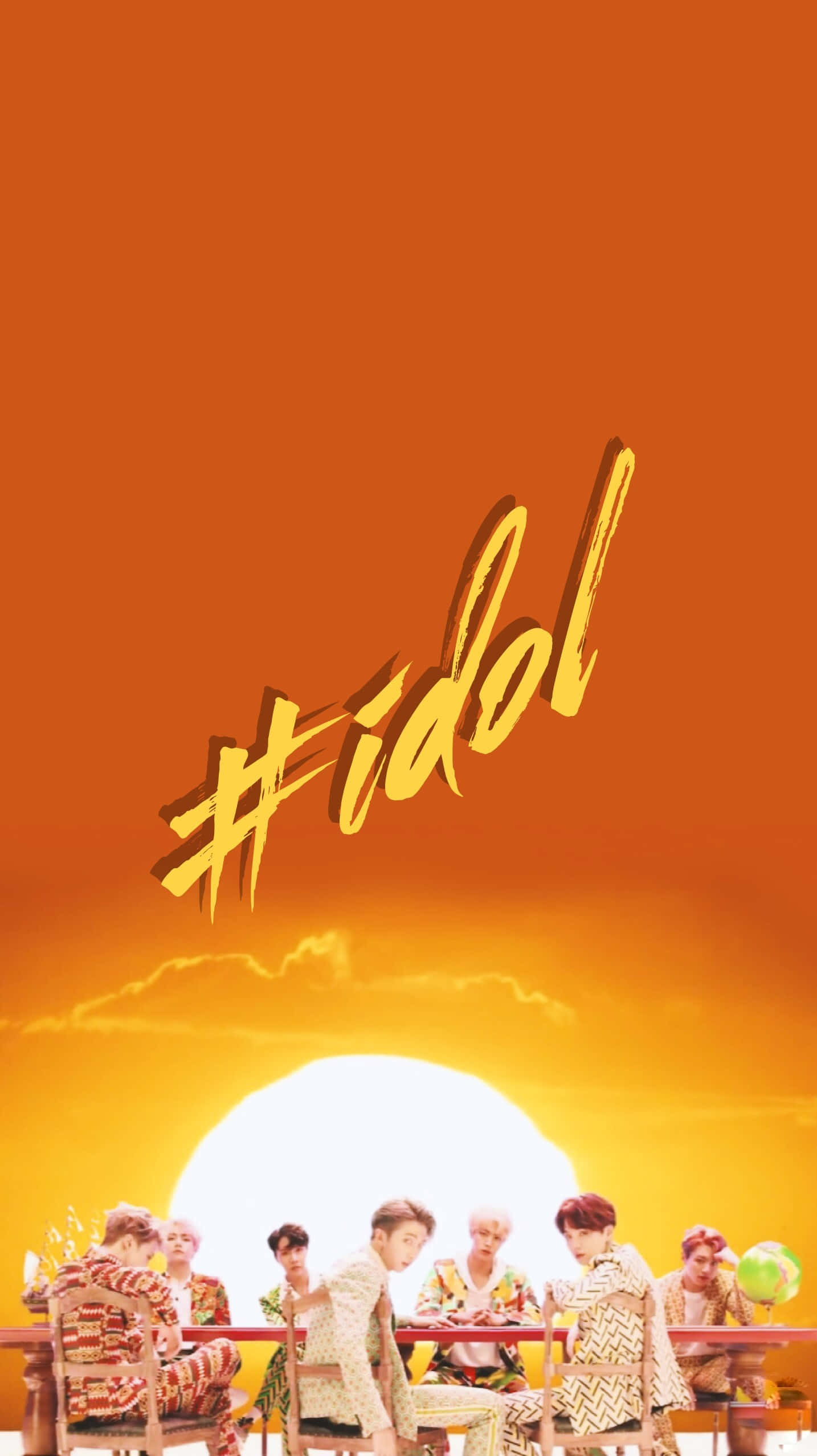 七個穿著圖案服裝的男人坐在一張桌子前，在明亮的橙色日落和「#idol」文字下。