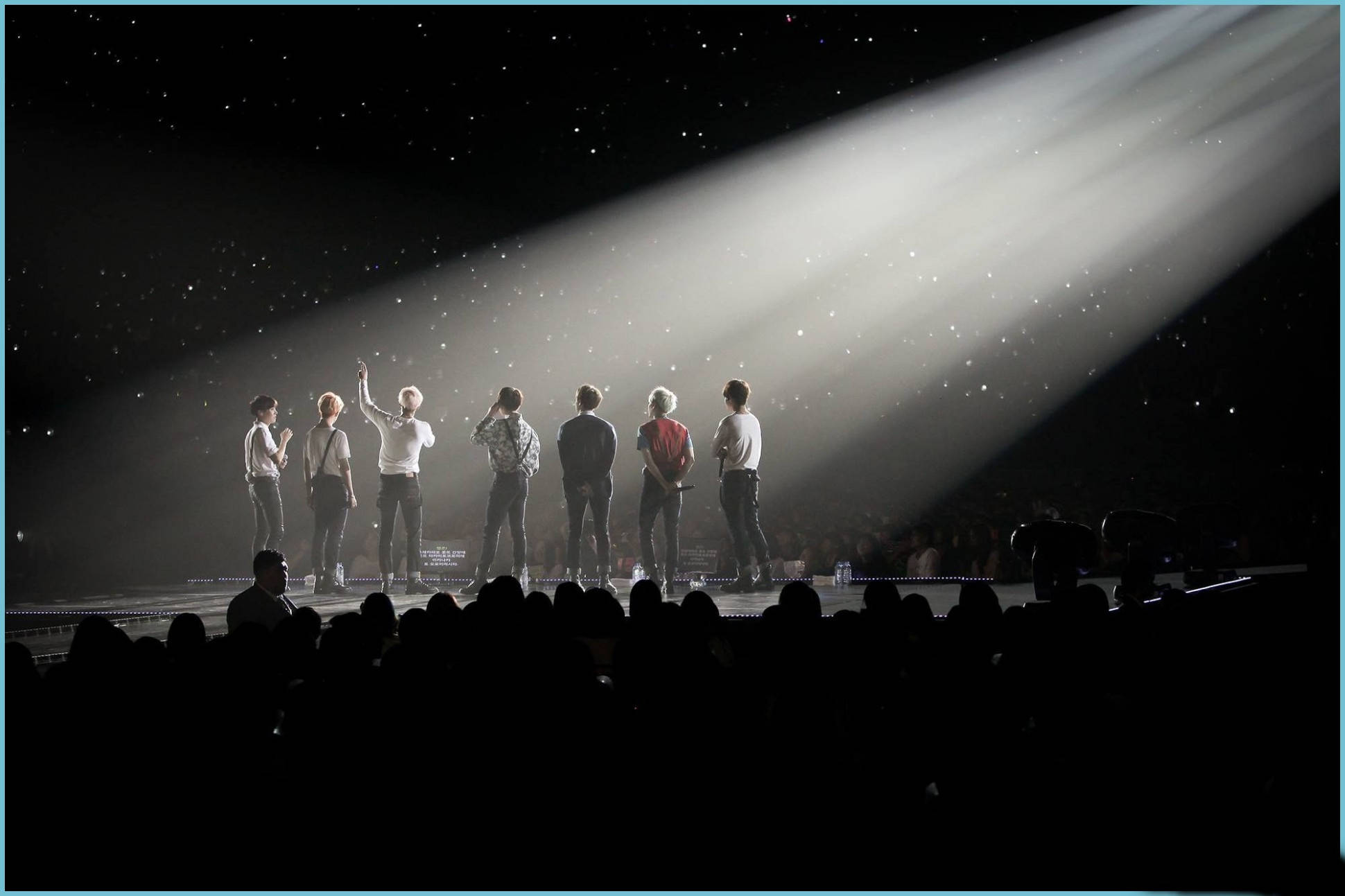 BTS 2021 桌面壁紙《演唱會聚光燈》 壁紙 — 七位表演者站在燈光昏暗的舞台上，沐浴在單一聚光燈下，背景是星空，下方觀眾形成剪影。