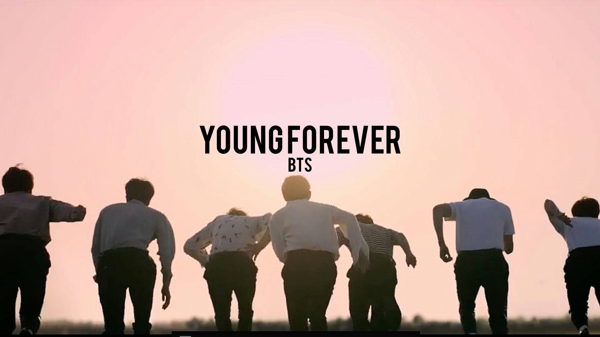 BTS 2020 年輕永恆 壁紙 — 七個剪影人物背光站立在發光的粉紅色日落前，並有粗體文字 YOUNGFOREVER BTS。