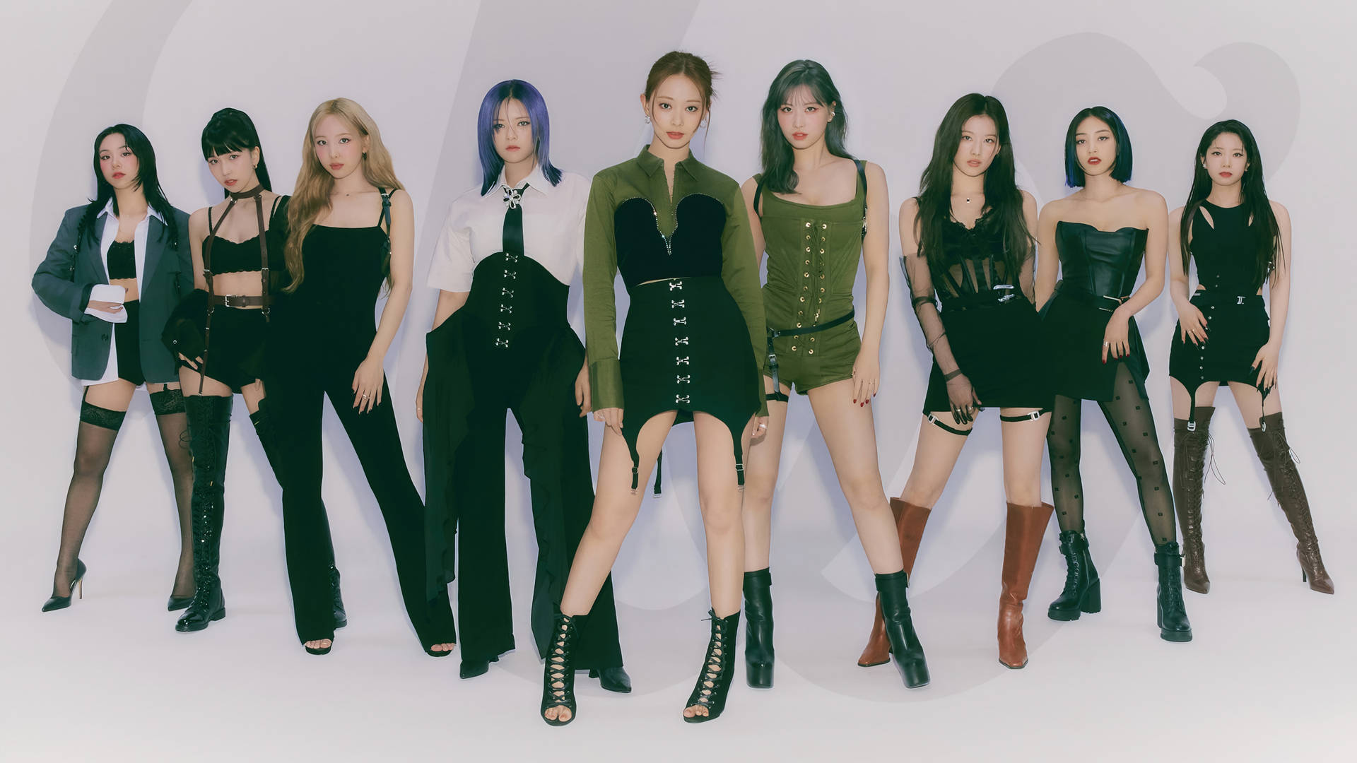 Twice 4K 綠黑配色造型 壁紙 — 七位時尚女性穿著前衛的黑色和橄欖色服裝，在極簡的白色工作室背景前自信地擺姿勢。