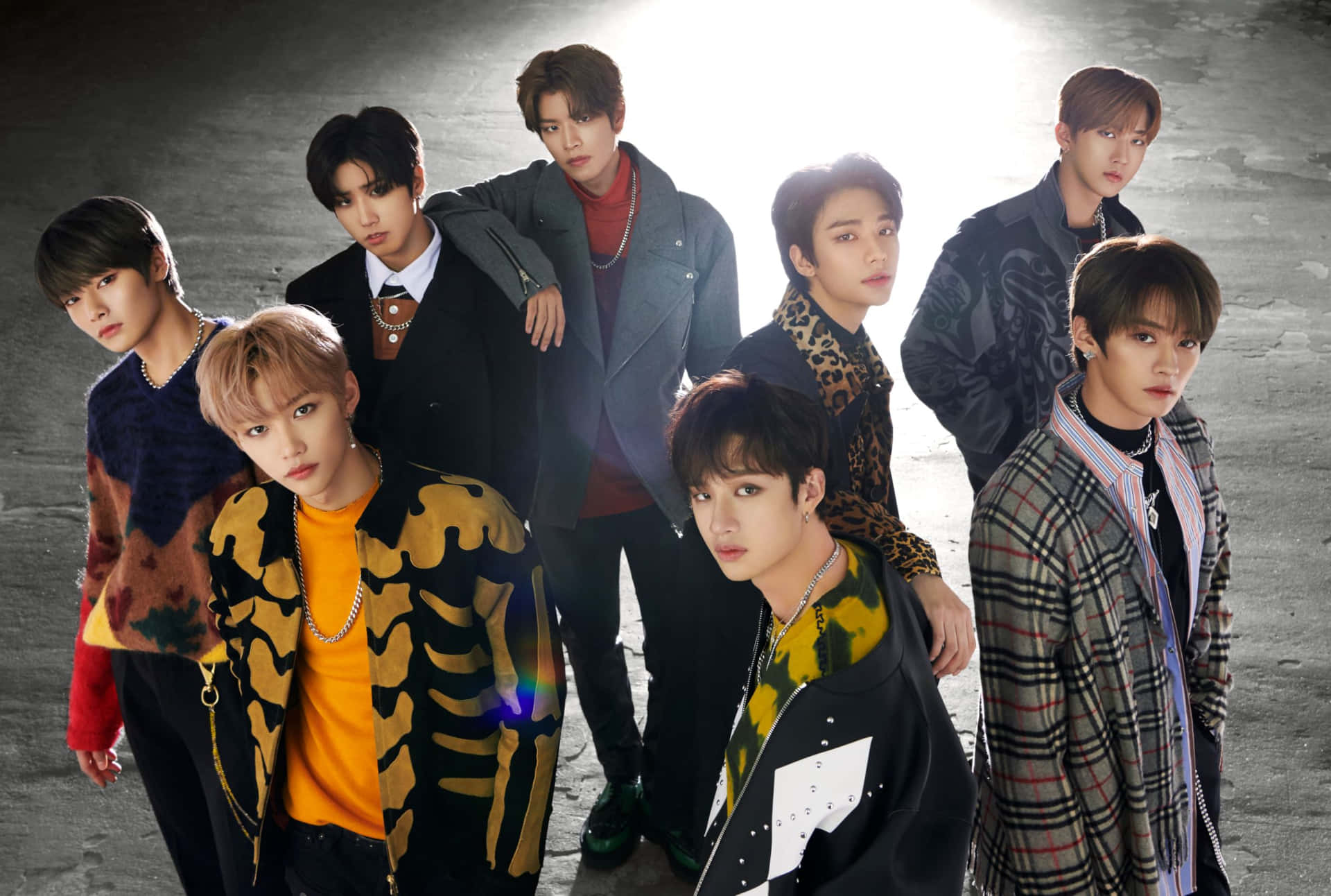 七位時尚的K-pop偶像身著大膽服裝，在背光下於混凝土牆前擺姿勢。 — Stray kids GIF 壁紙