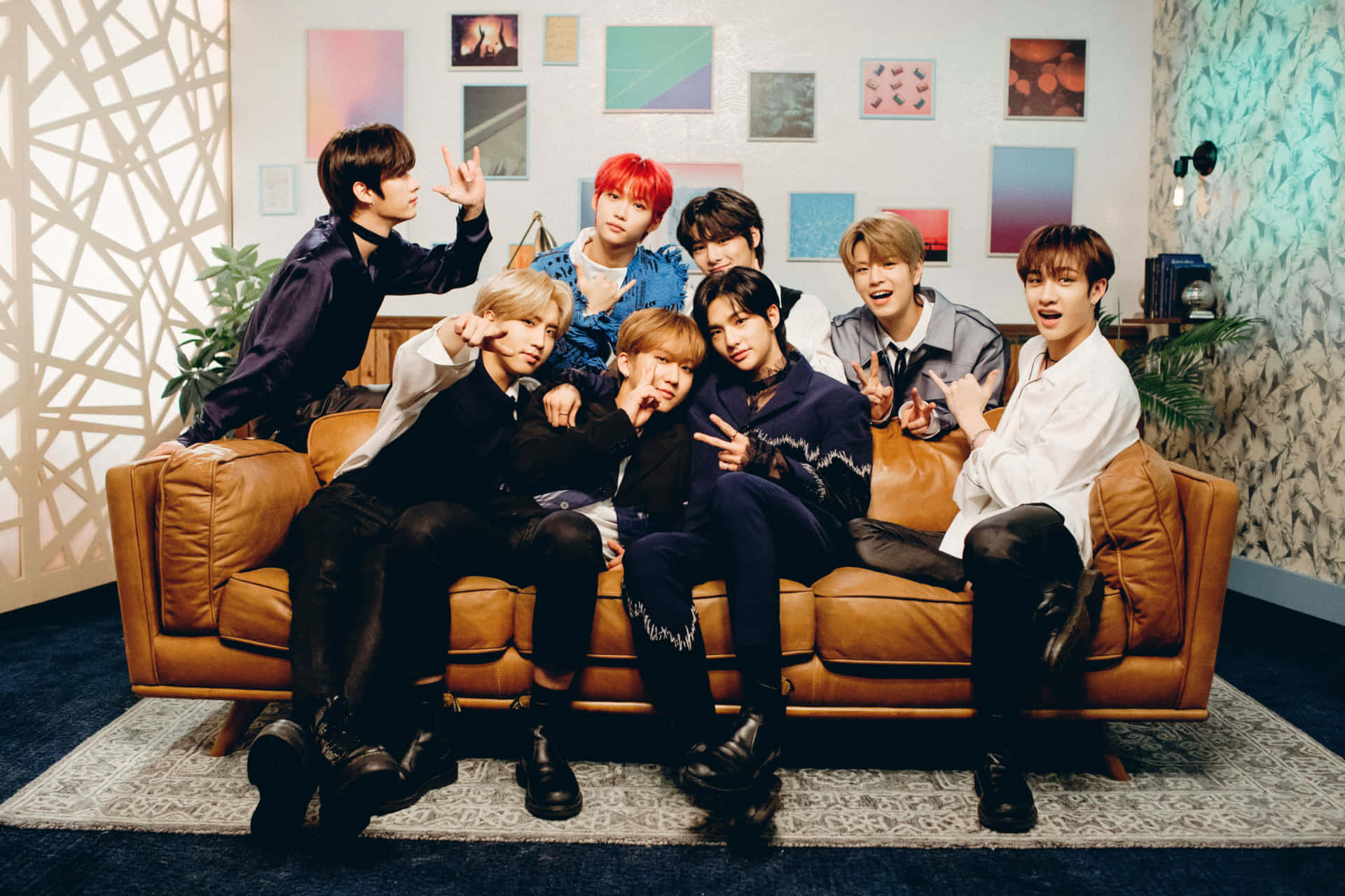 七位穿著時尚的年輕男士在現代房間的棕色皮革沙發上擺姿勢。 — Stray kids GIF 壁紙