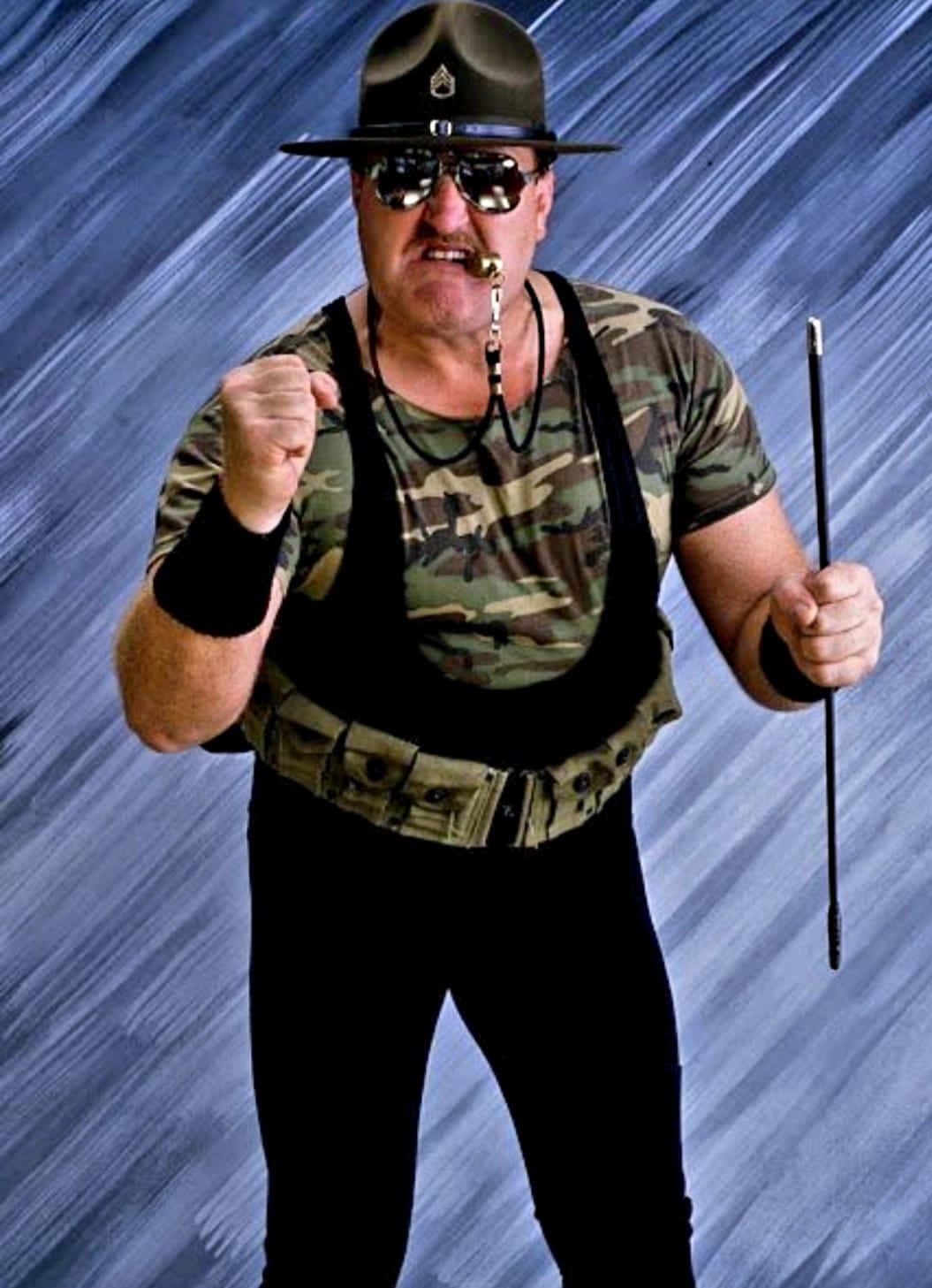 身穿軍裝、戴著太陽眼鏡的男子，手持手杖，握拳擺姿勢。 — WWE GIF 壁紙