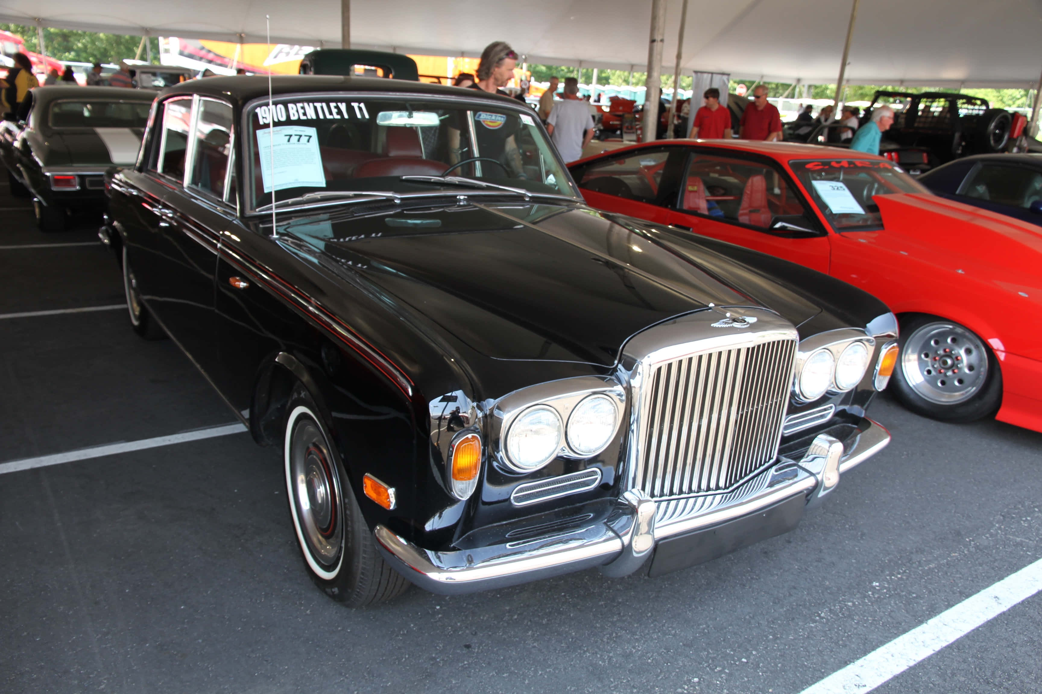 Bentley T1 桌布 壁紙 — 一輛閃亮的黑色1960年賓利T1轎車在經典車拉力賽的帳篷下展出，旁邊有一輛紅色跑車。