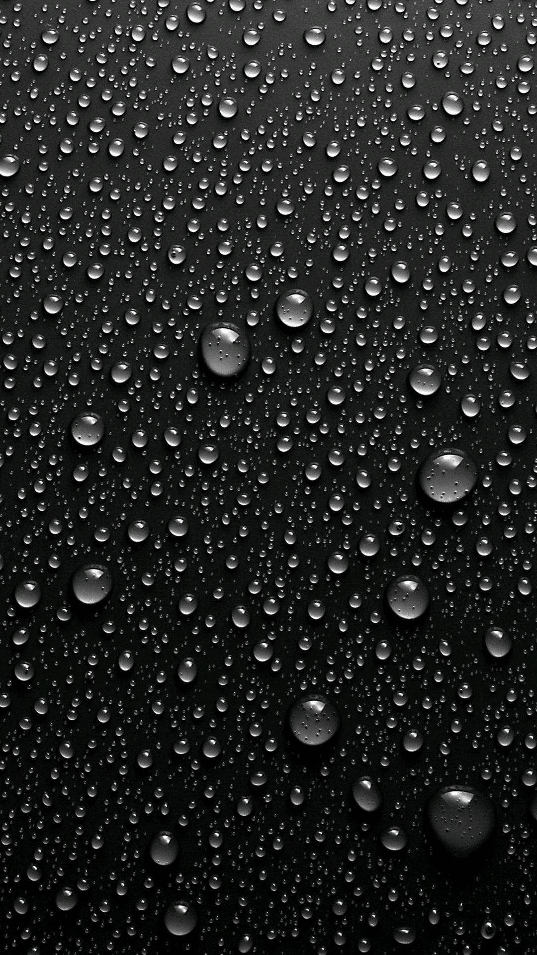 黑色表面上反射光線的雨滴特寫。