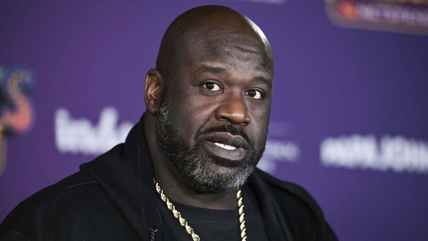  壁紙 — Shaquille O'Neal 身穿黑色連帽衫和金色鏈條，背景為紫色品牌背景。
