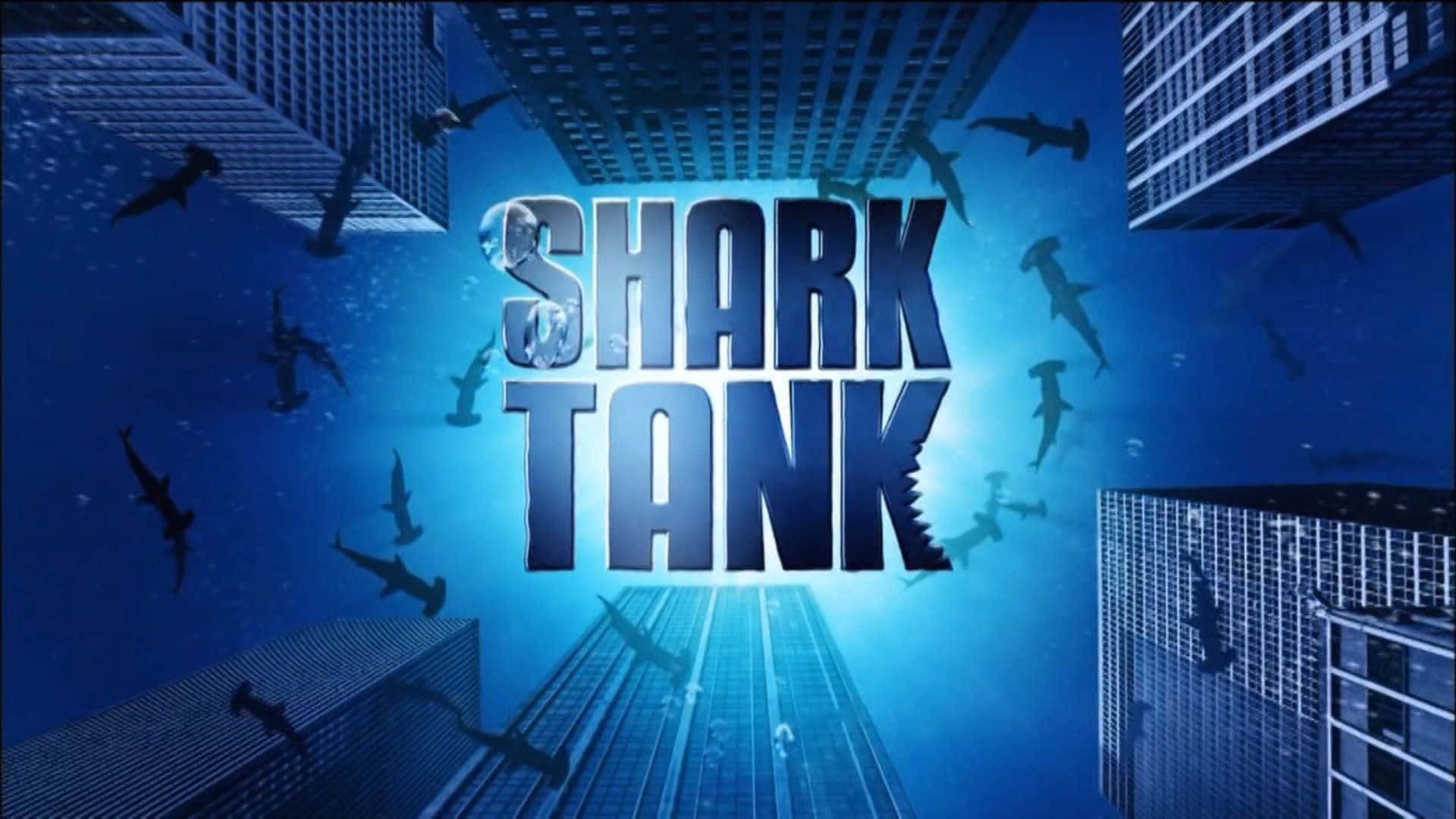  壁紙 — Shark Tank 標誌喺水下發出藍光，鯊魚喺超現實城市景觀中嘅摩天大樓之間游嚟游去。