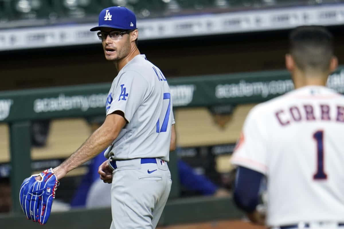  壁紙 — 身穿道奇隊球衣的棒球選手在球場燈光下，比賽期間拿著手套在場上行走。