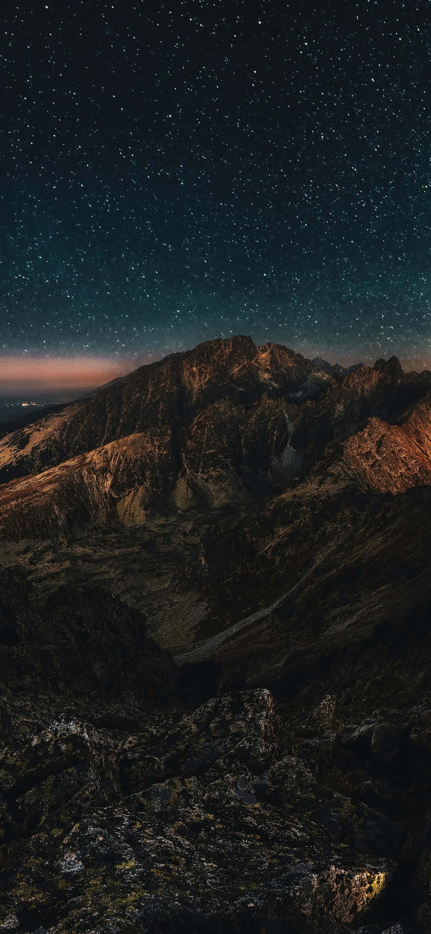  壁紙 — 在深藍綠色夜空下，密集的星幕籠罩著沐浴在暮光中的雄偉山脈。