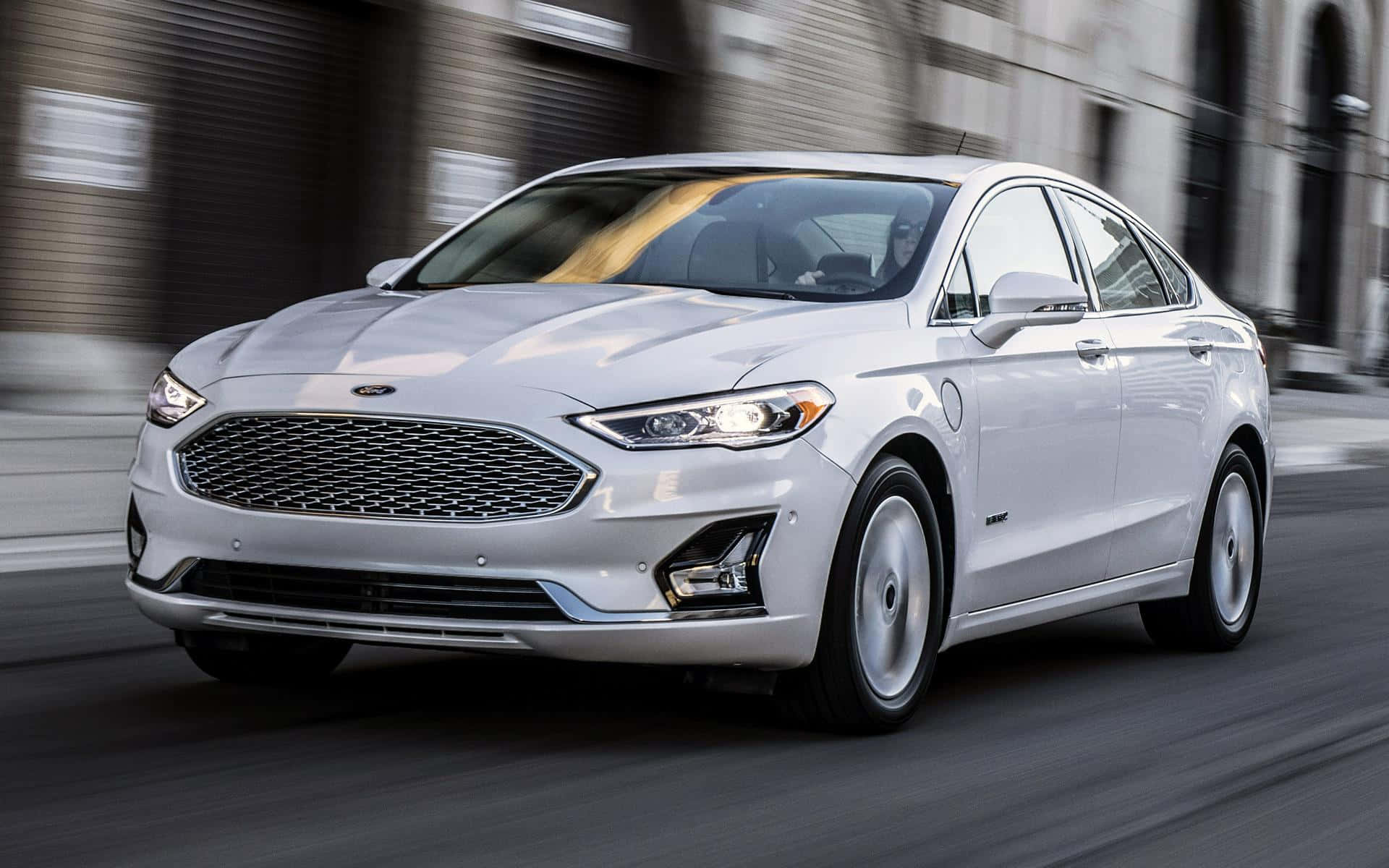 Ford Fusion 桌布 壁紙 — 一輛時尚的白色福特Fusion Hybrid在城市的街道上奔馳，城市建築物呈現動態模糊效果。