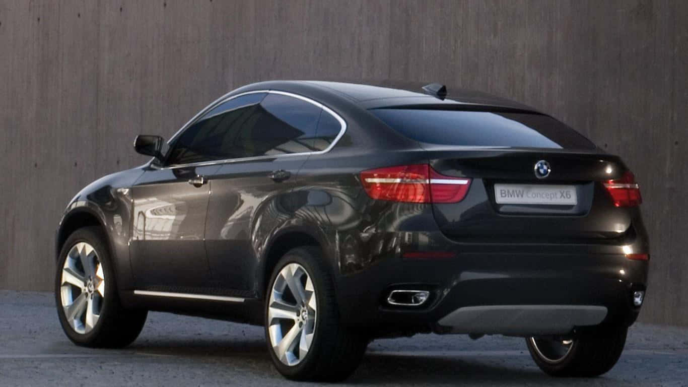 Bmw X6 桌布 壁紙 — 一輛時尚的黑色BMW Concept X6轎跑SUV停在有紋理的混凝土牆前，牆面帶有反射效果。