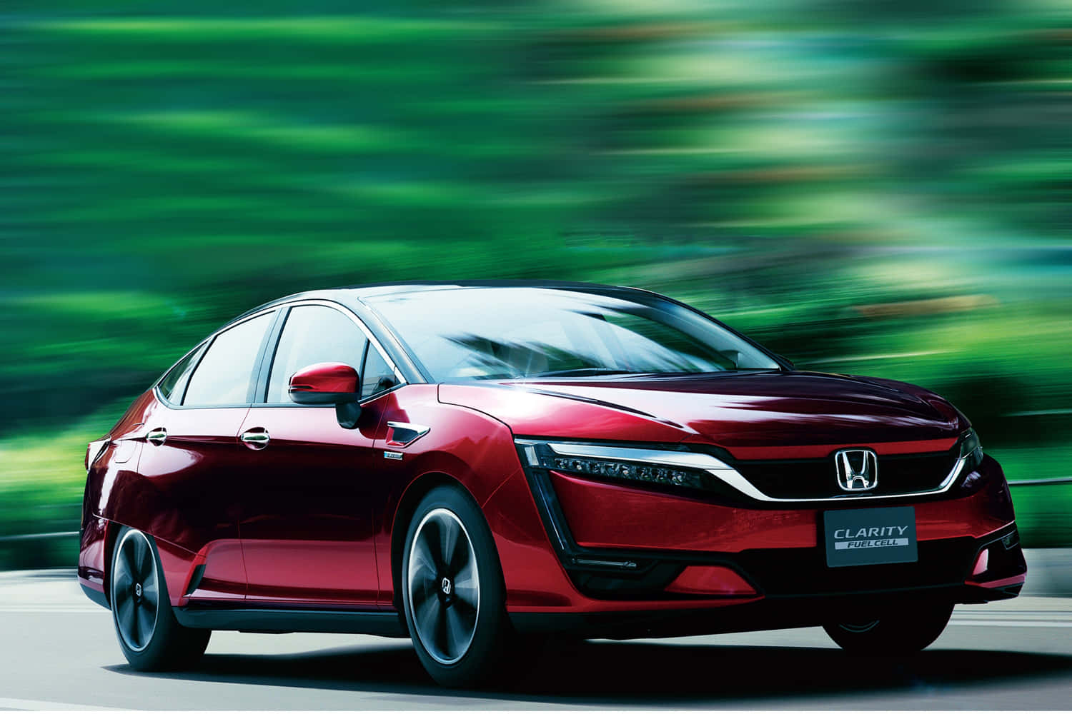 Honda Clarity 桌布 壁紙 — 一輛時尚的紅色本田Clarity插電式混合動力轎車在充滿活力的綠色動態模糊背景下行駛。