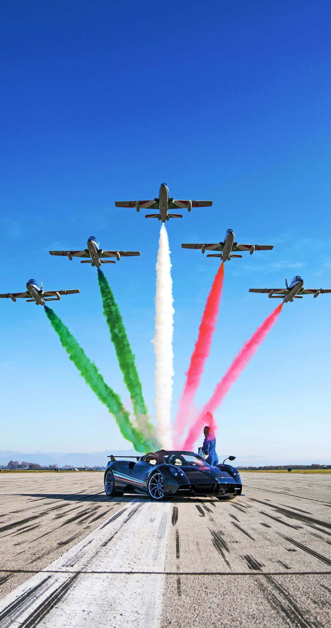 Pagani Zonda Tricolore 桌布 壁紙 — 一架時尚的藍色跑車在跑道上，四架噴射機在上空飛過，留下綠色、白色和紅色的煙霧，形成意大利國旗。