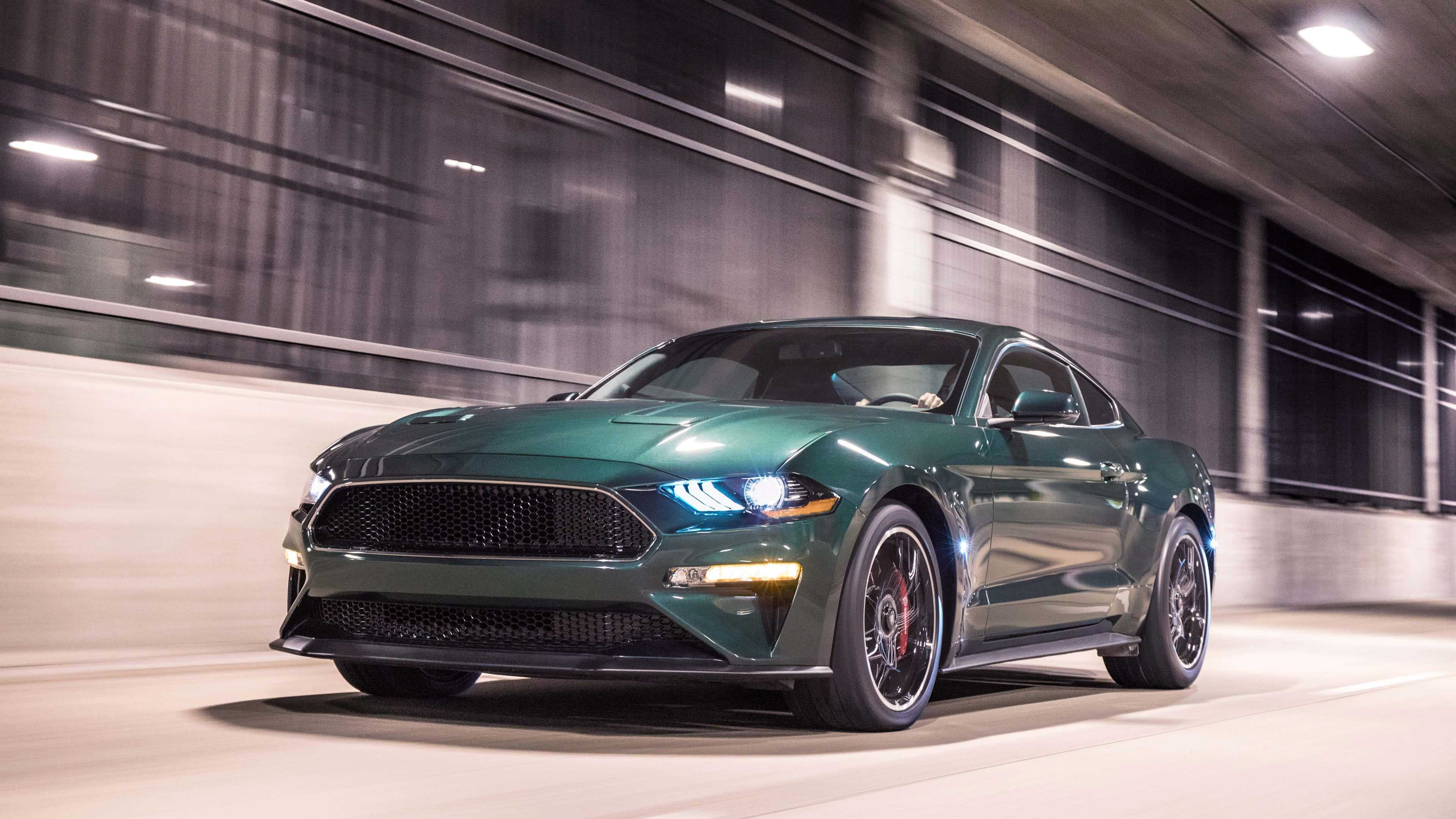 Ford Mustang Bullitt 桌布 壁紙 — 一輛時尚的綠色福特野馬在昏暗的城市隧道中疾馳，背景帶有動態模糊效果。
