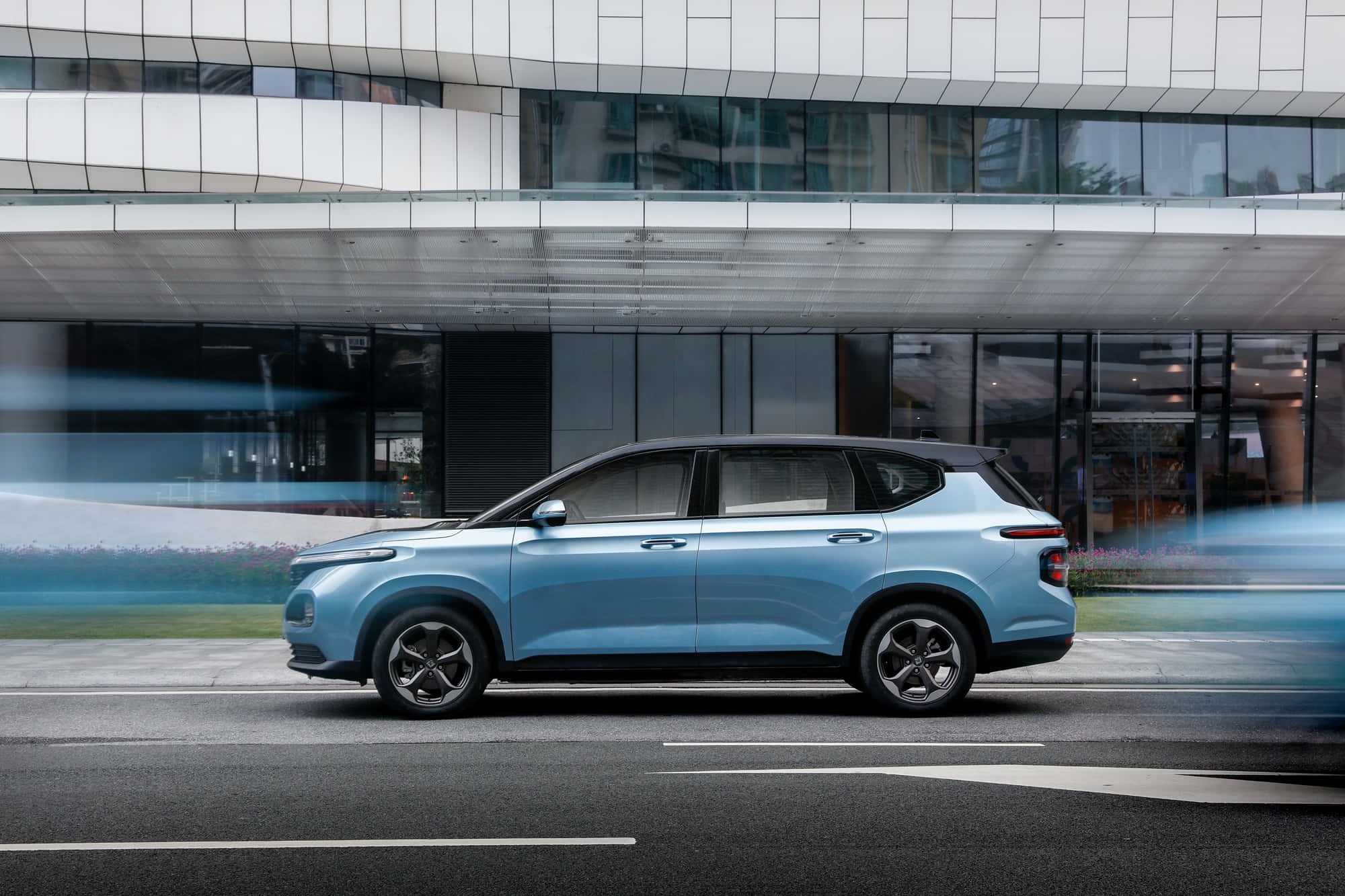 Baojun 桌布 壁紙 — 一輛時尚的淺藍色SUV在現代玻璃建築旁駛過，背景帶有動態模糊條紋。