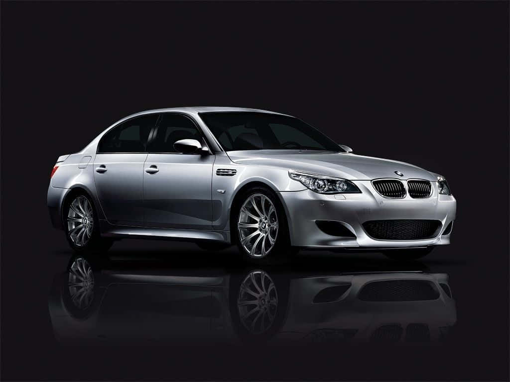 Bmw M5 桌布 壁紙 — 一輛時尚的銀色BMW M5轎車在攝影棚燈光下閃耀，在深色光澤地板上完美倒映。