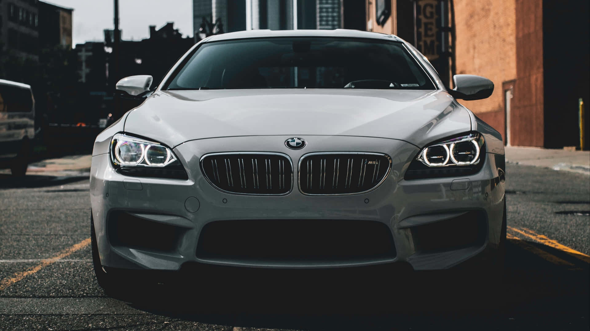 Bmw M6 桌布 壁紙 — 一輛時尚的銀色BMW M6跑車停在粗糙的城市街道上，車頭燈閃爍，背景是磚砌建築。