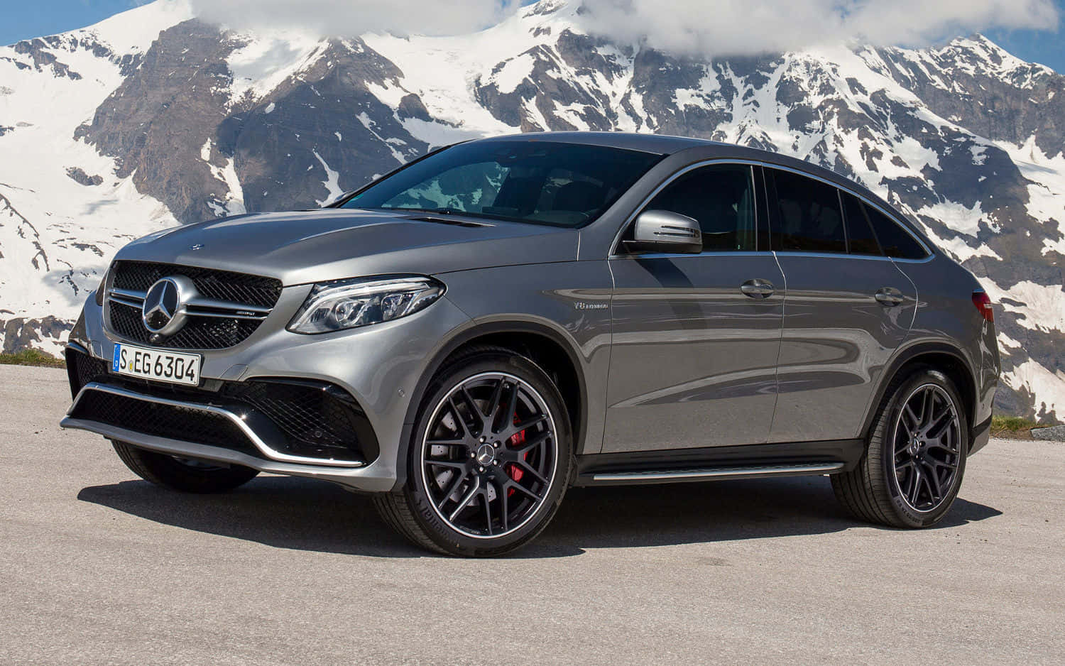 Mercedes Benz Gle-class 桌布 壁紙 — 一架時尚的銀色Mercedes-AMG GLE63 S Coupe停泊在山路上，背後是白雪覆蓋的山峰，在明亮的日光下。