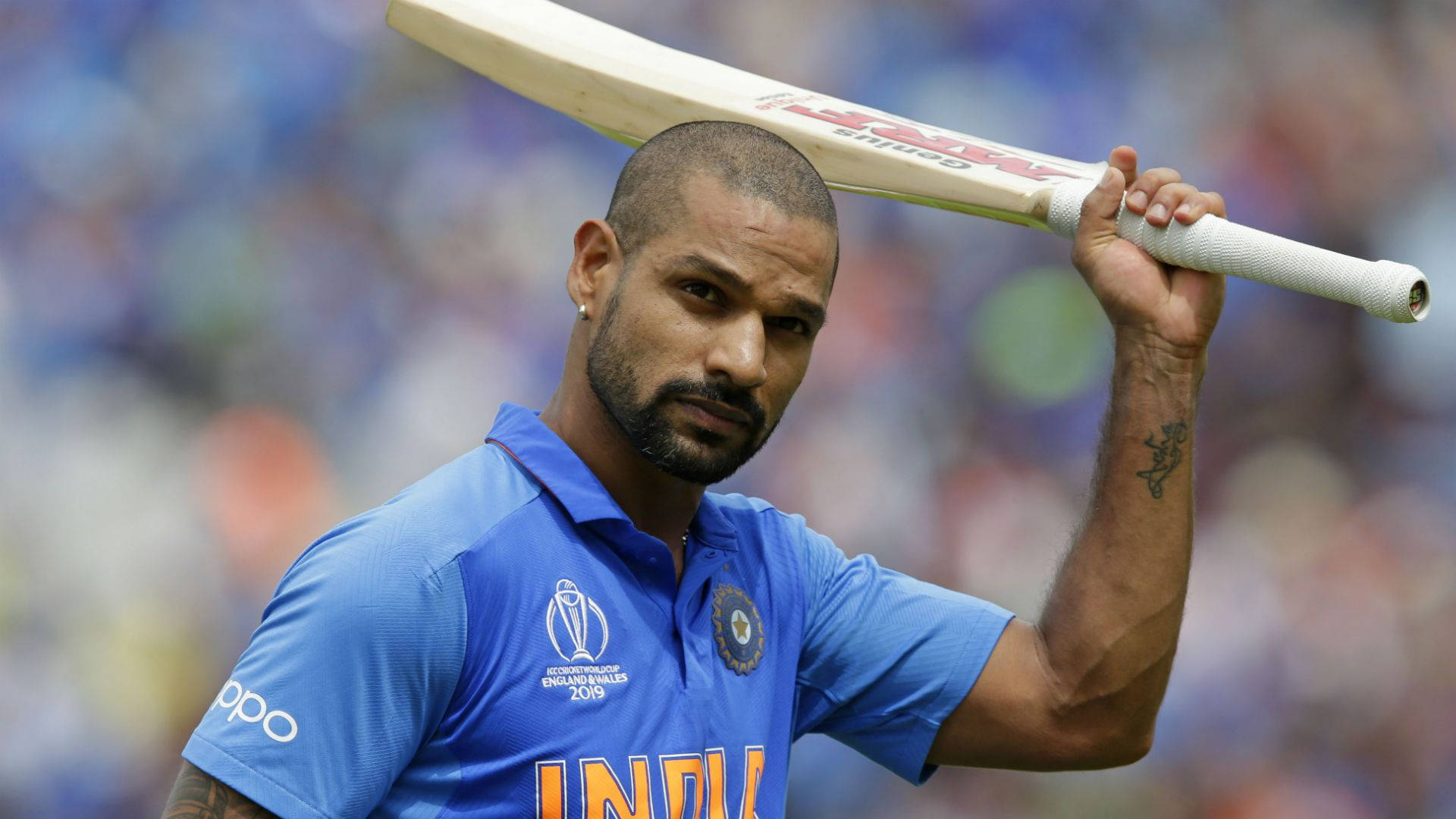 Shikhar Dhawan 高舉球棒 壁紙 — 印度板球運動員在日間比賽中穿著藍色隊服，將球棒扛在肩上。