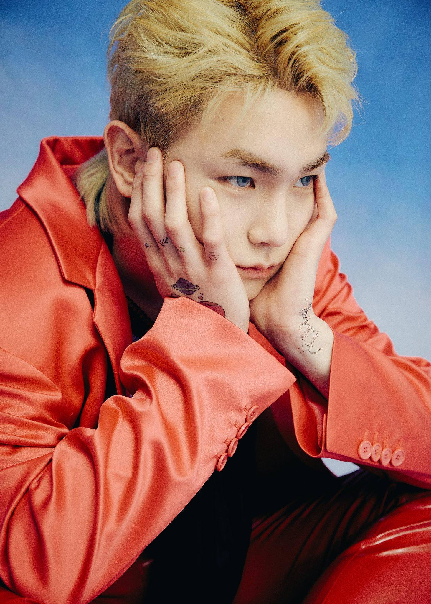 Shinee Blue-Eyed Key 壁紙 — 一位金髮紋身年輕男子身穿閃亮紅色西裝，雙手托頭，背景為藍色漸變。