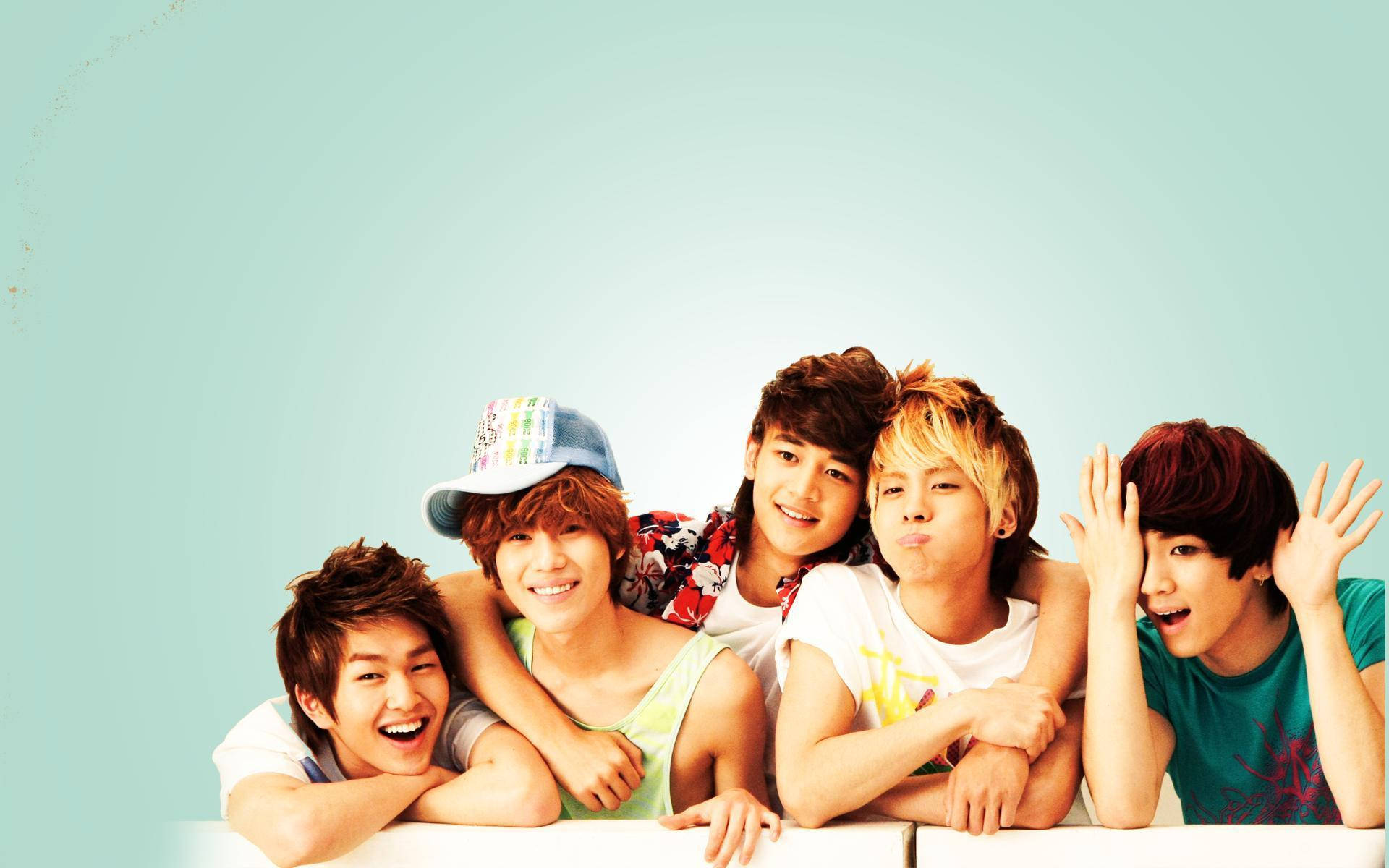 SHINee 放鬆合照 壁紙 — 五位年輕男子，頭髮色彩繽紛，表情俏皮，靠喺白色邊緣上，背景係柔和嘅青綠色。