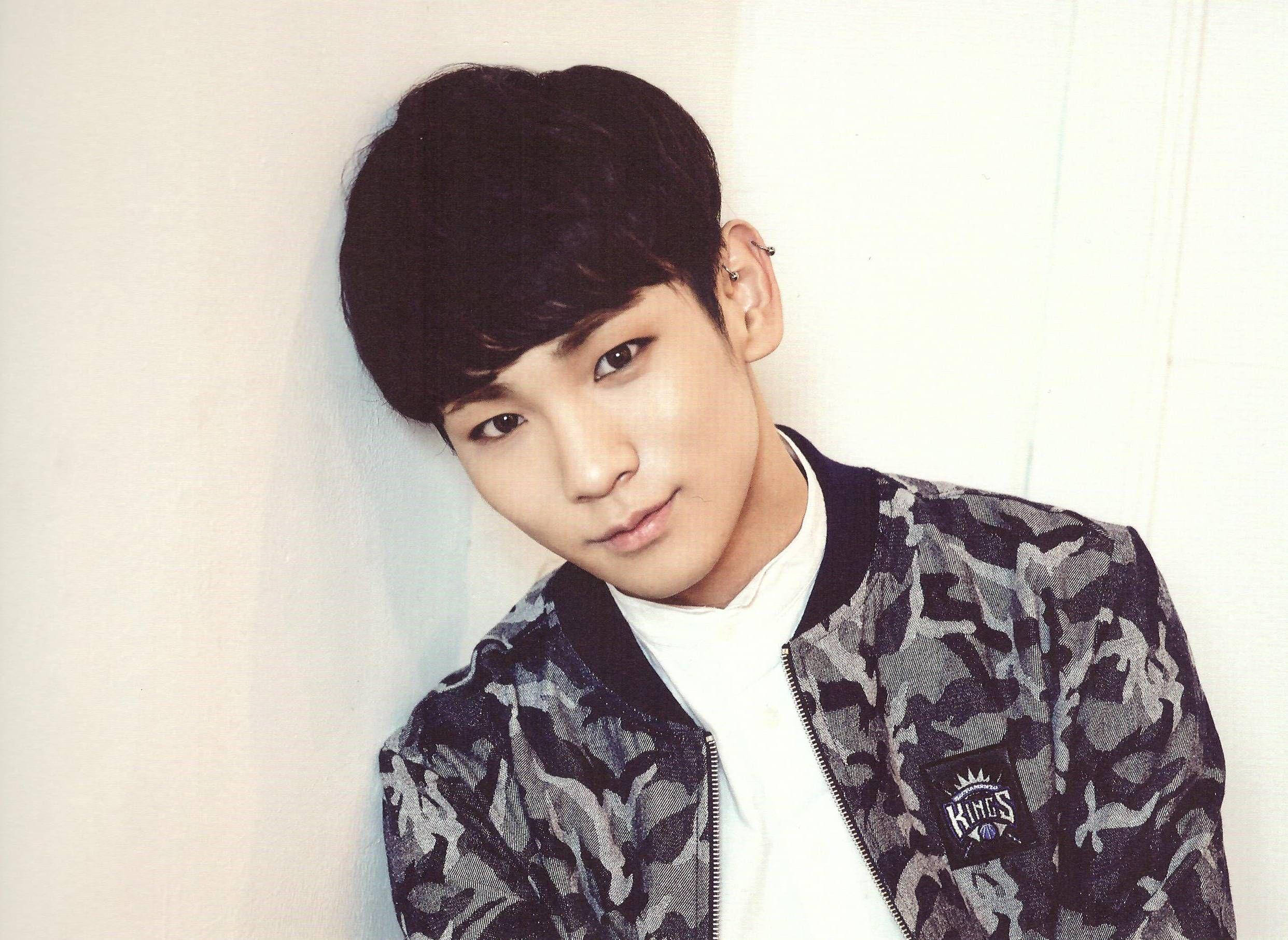SHINee Key 特寫照 壁紙 — 一位黑髮年輕男子靠著素牆，身穿迷彩轟炸機外套內搭白色T恤。