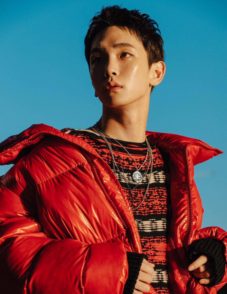 SHINee Key 紅色戶外造型 壁紙 — 一位身穿閃亮紅色羽絨外套的年輕男子站在清澈的藍天下，自信地向上凝視。