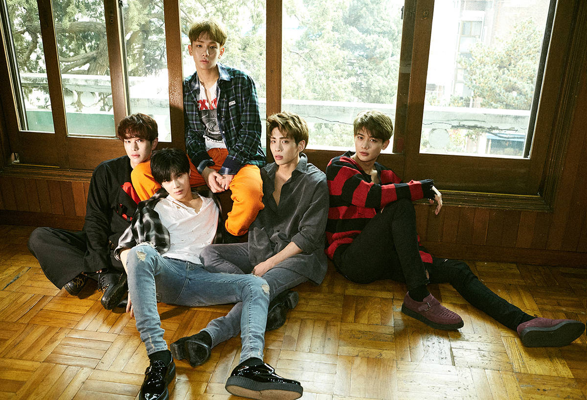 帥氣 SHINee 成員 壁紙 — 五位身穿休閒服的年輕男子在木地板上放鬆擺姿勢，旁邊有大窗戶，窗外有綠植。