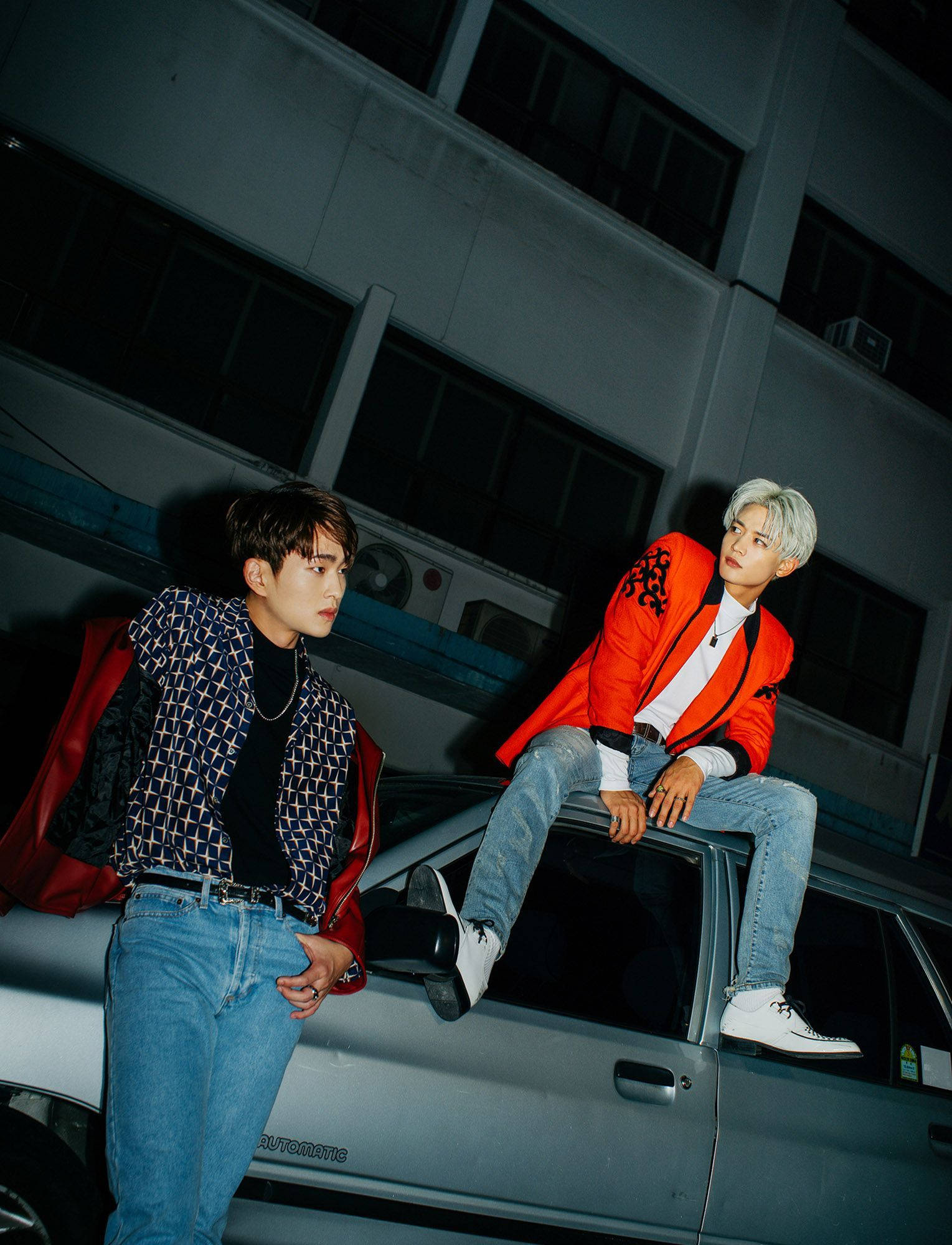 Shinee Onew And Min-Ho 壁紙 — 兩位時尚男士在夜間，以昏暗的城市建築為背景，自信地站在車頂上擺姿勢。