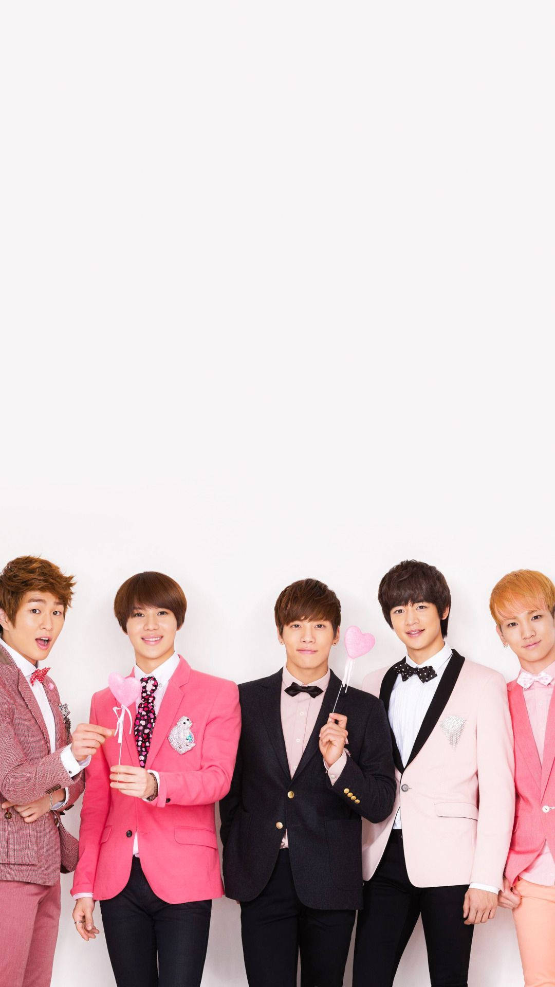SHINee 粉紅美學 壁紙 — 五位年輕男士穿著時尚的粉紅色和黑色西裝，在純白色背景前開心地擺姿勢，手持心形道具。