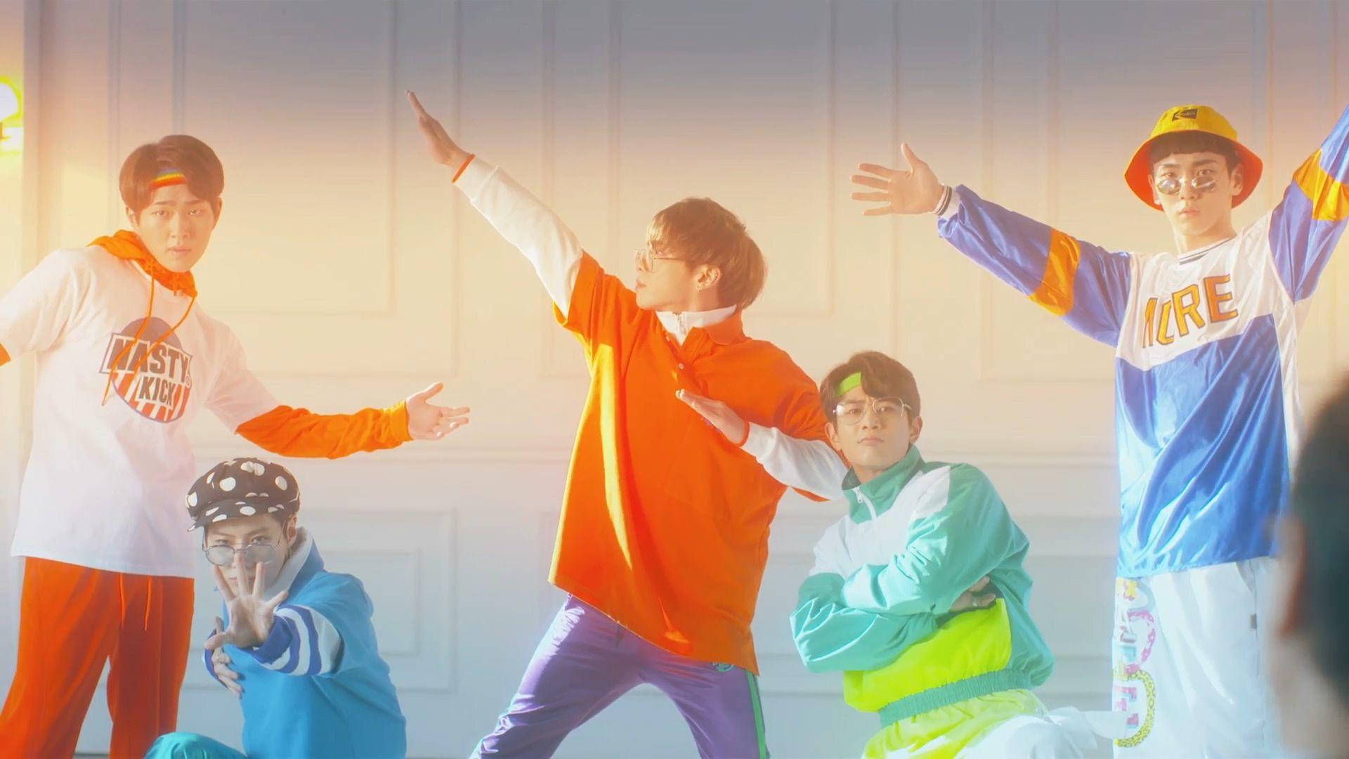 SHINee 色彩繽紛合照 壁紙 — 五名年輕男子穿著充滿活力的90年代街頭服飾，在柔和照明的鑲板牆前擺出動態姿勢。