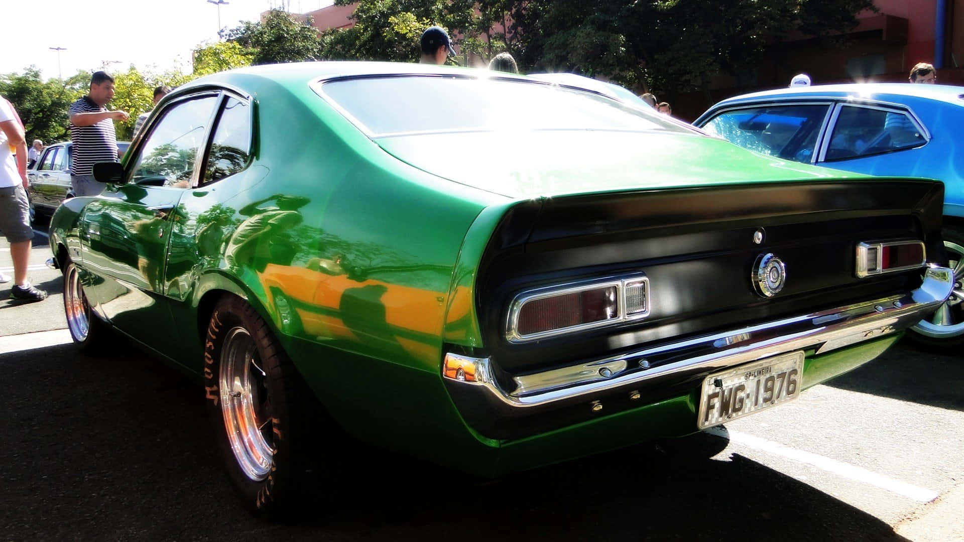 Ford Maverick 桌布 壁紙 — 一輛閃亮的綠色經典肌肉車，帶有鍍鉻細節和1976年車牌，停在戶外明亮的陽光下。