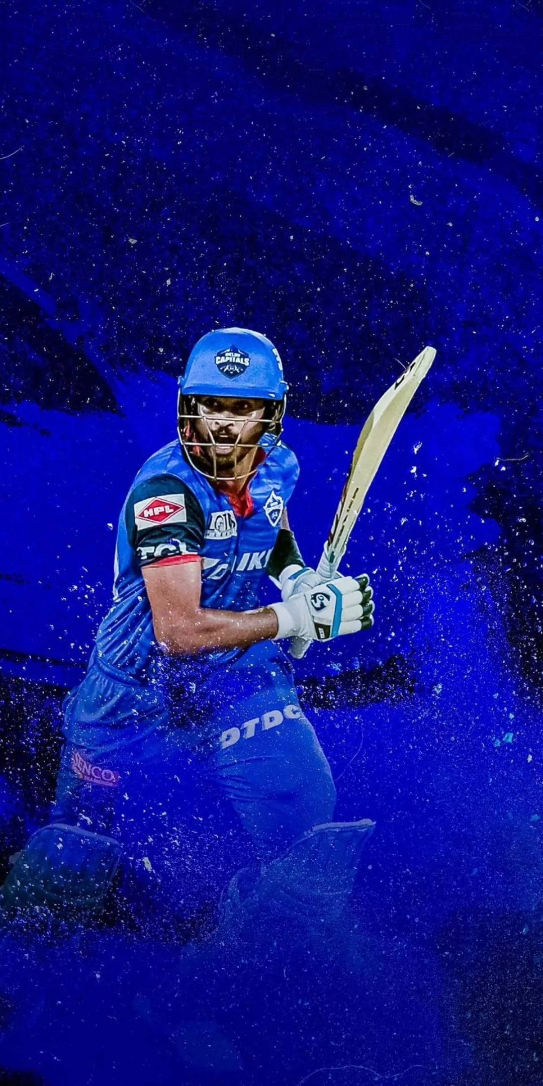 Shreyas Iyer 帶領德里首都隊前進 壁紙 — 一名身穿藍色球衣的板球運動員在深色背景中，於動態藍色粒子效果下揮動球棒。