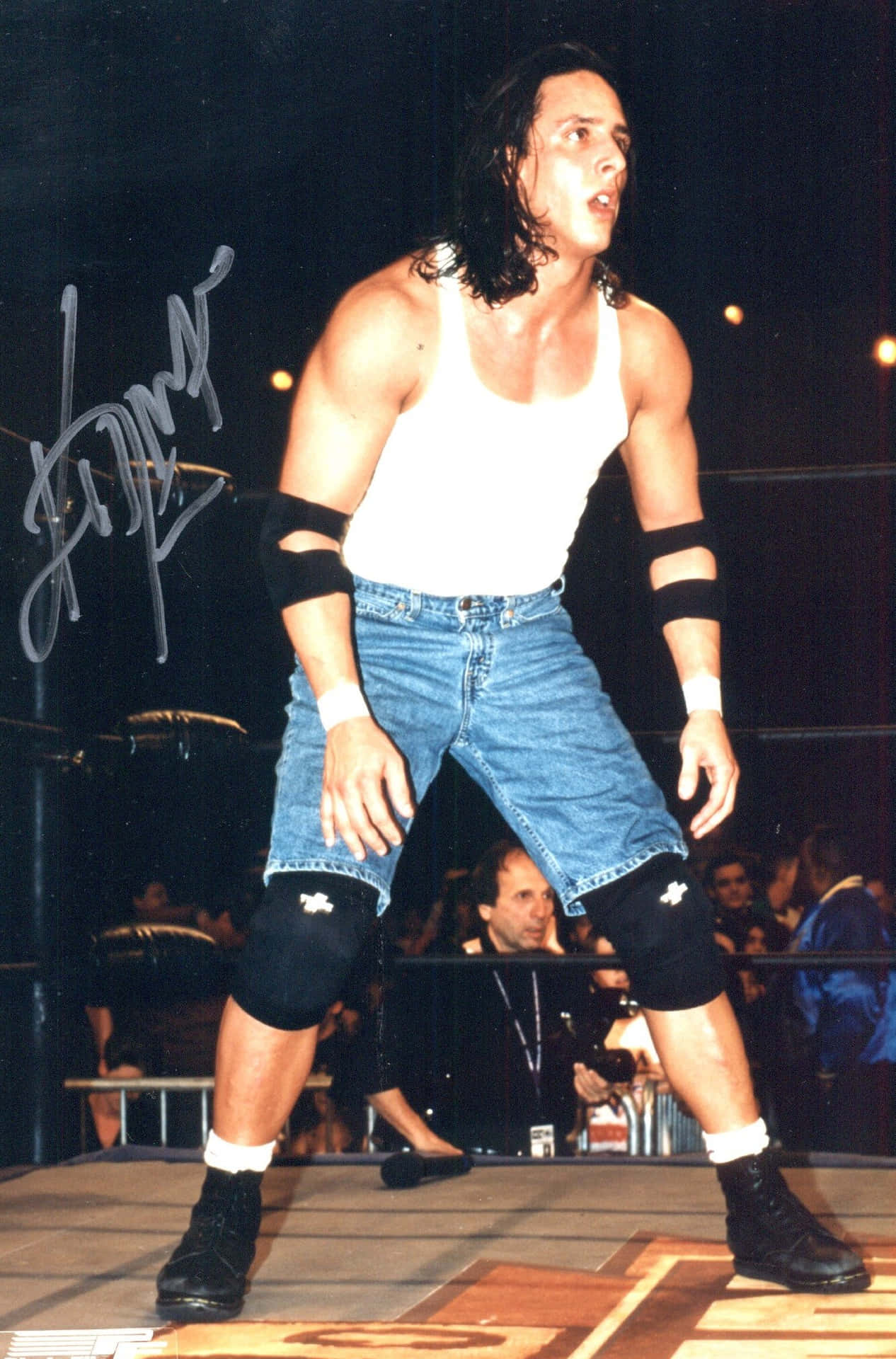  壁紙 — 摔角手 Chris Jericho 身穿白色背心和牛仔短褲，在場館燈光下帶著強烈表情站在擂台上。