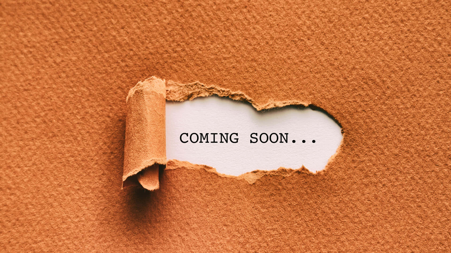 撕破的棕色紙張露出「COMING SOON...」文字。