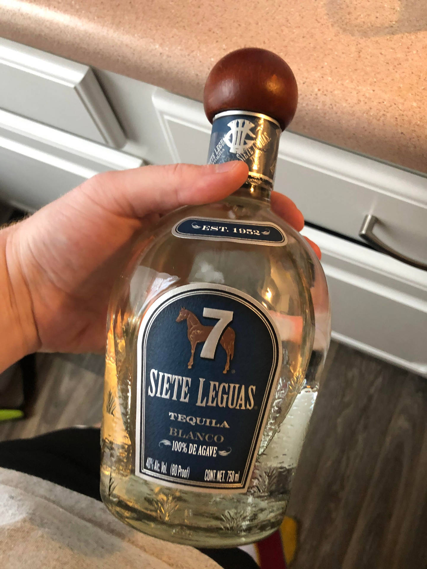 在廚房裏拿着一瓶 Siete Leguas 龍舌蘭酒的手。