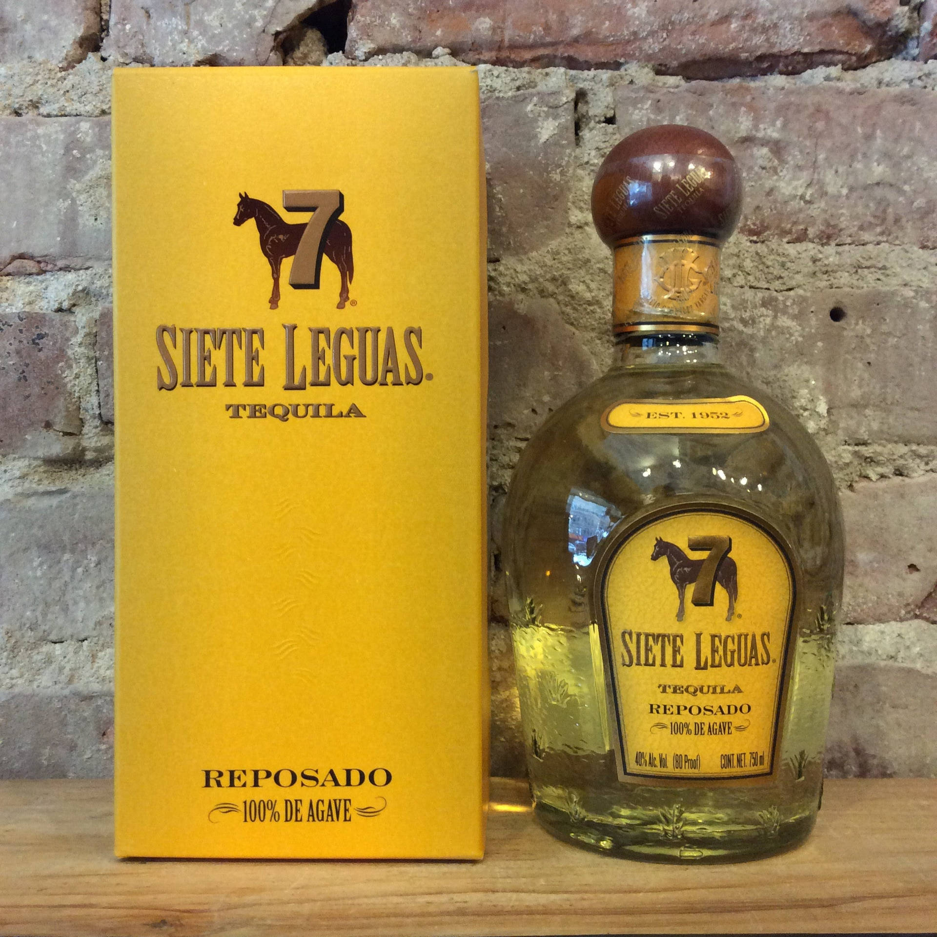 Siete Leguas龍舌蘭酒瓶和盒子放在木質表面上，背景是磚牆。