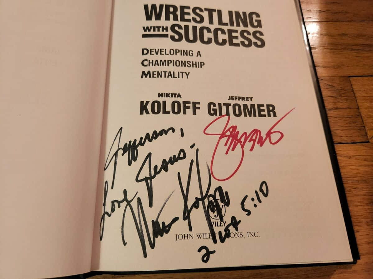  壁紙 — Wrestling with Success 書籍的簽名本，打開在標題頁，木桌上有多個親筆簽名。