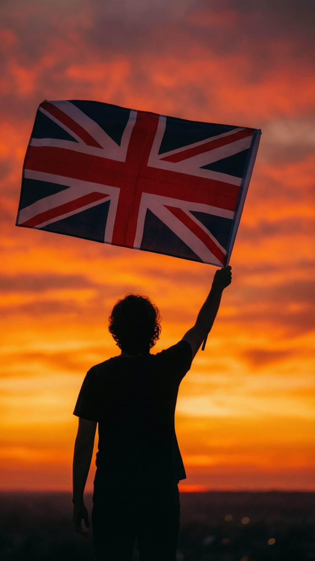 人在鮮豔橙色日落天空前手持英國國旗
