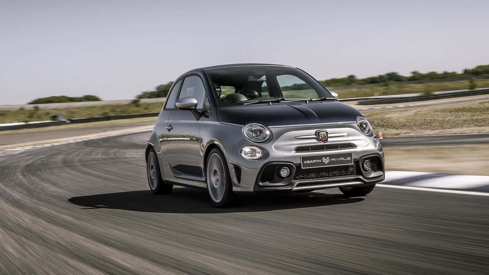Fiat 500 桌布 壁紙 — 一輛銀色嘅Fiat 500 Abarth喺明亮日光下，喺賽道彎位高速飛馳，瀝青路上帶有動態模糊效果。