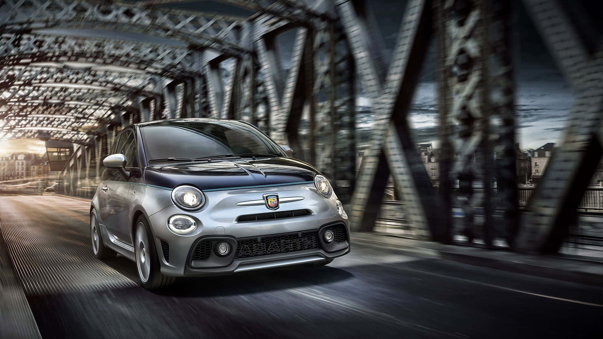 Fiat 500l 桌布 壁紙 — 一輛銀色Fiat 500在鋼橋下行駛，動態模糊，金色時刻照明。