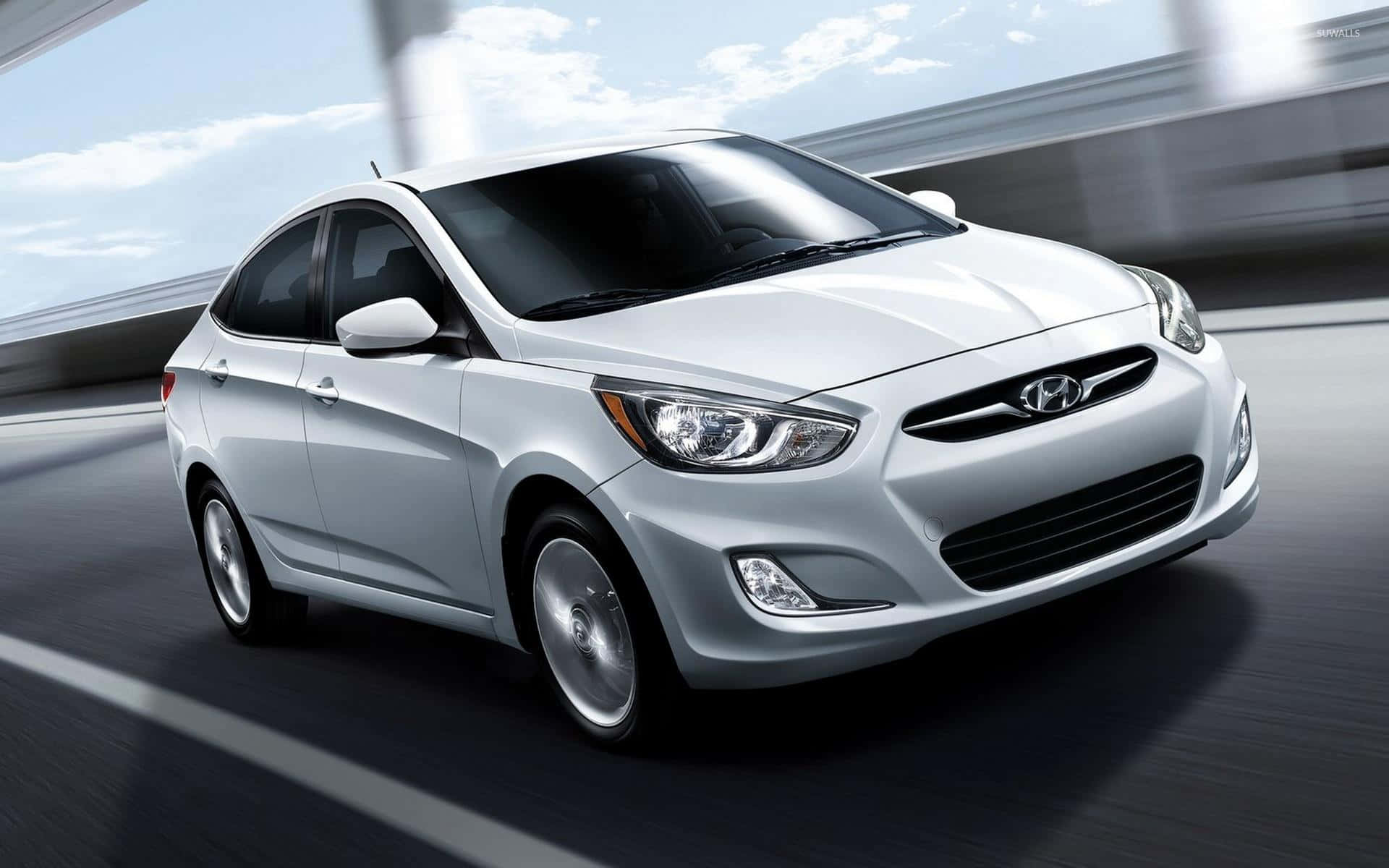 Hyundai Accent 桌布 壁紙 — 一輛時尚的銀色現代房車在藍天白雲下高速行駛。