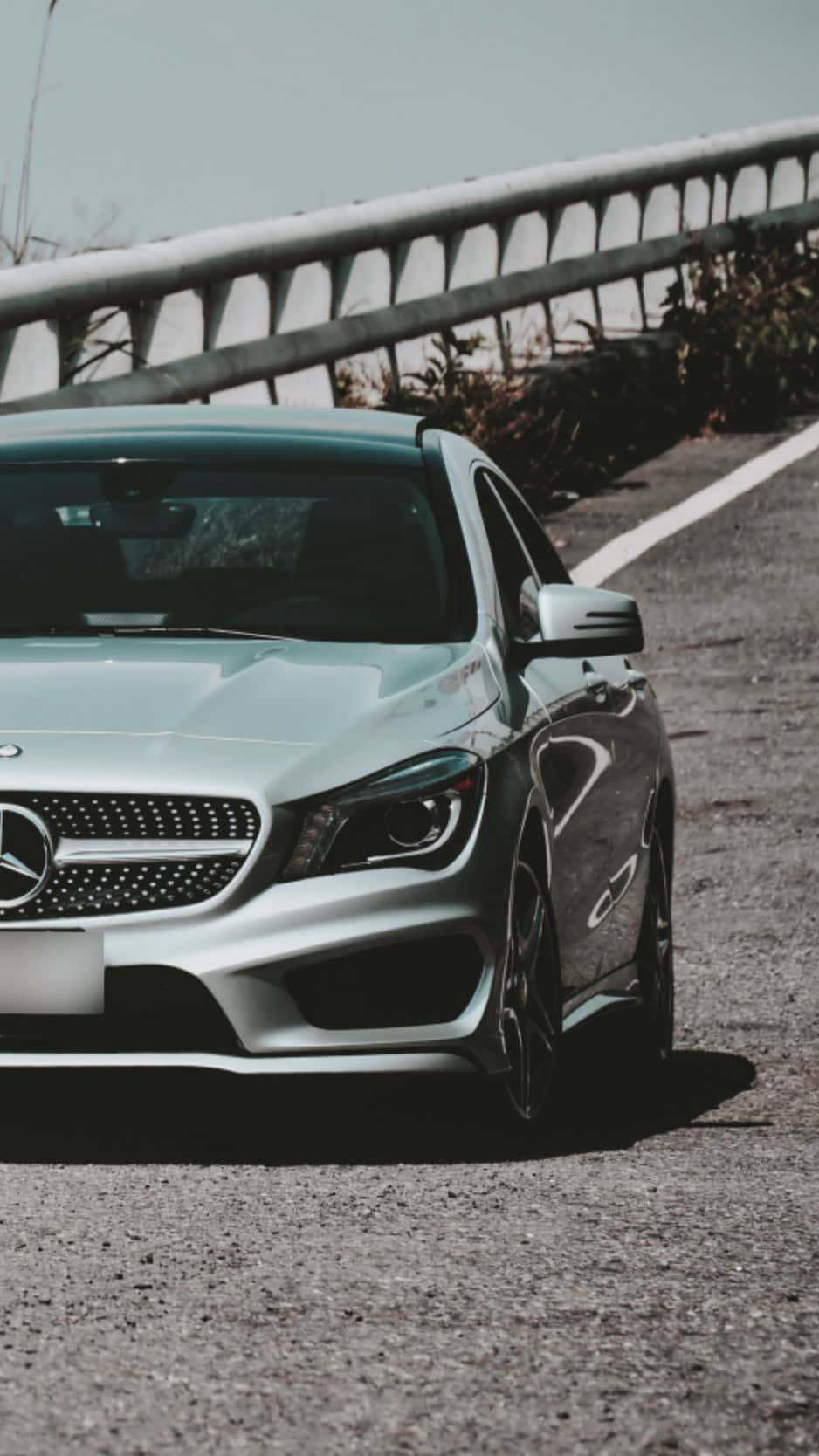Mercedes Benz Cla-class 桌布 壁紙 — 一架時尚的銀色梅賽德斯-奔馳跑車停泊在碎石路邊，背景是明亮的天空和金屬護欄。