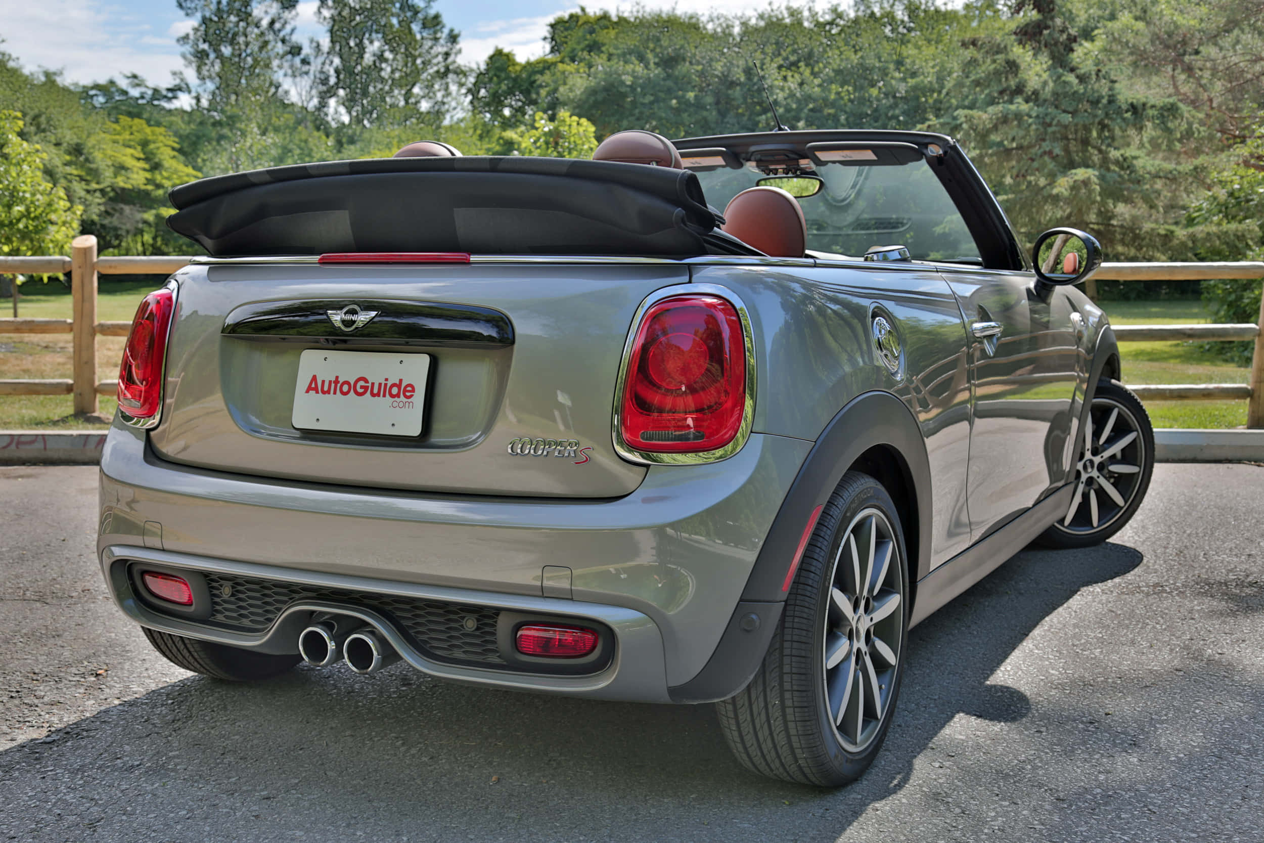 Mini Cooper S Convertible 桌布 壁紙 — 一輛銀色MINI Cooper S開篷車停在瀝青路上，車頂敞開，周圍有綠樹和木柵欄，在明亮的日光下。
