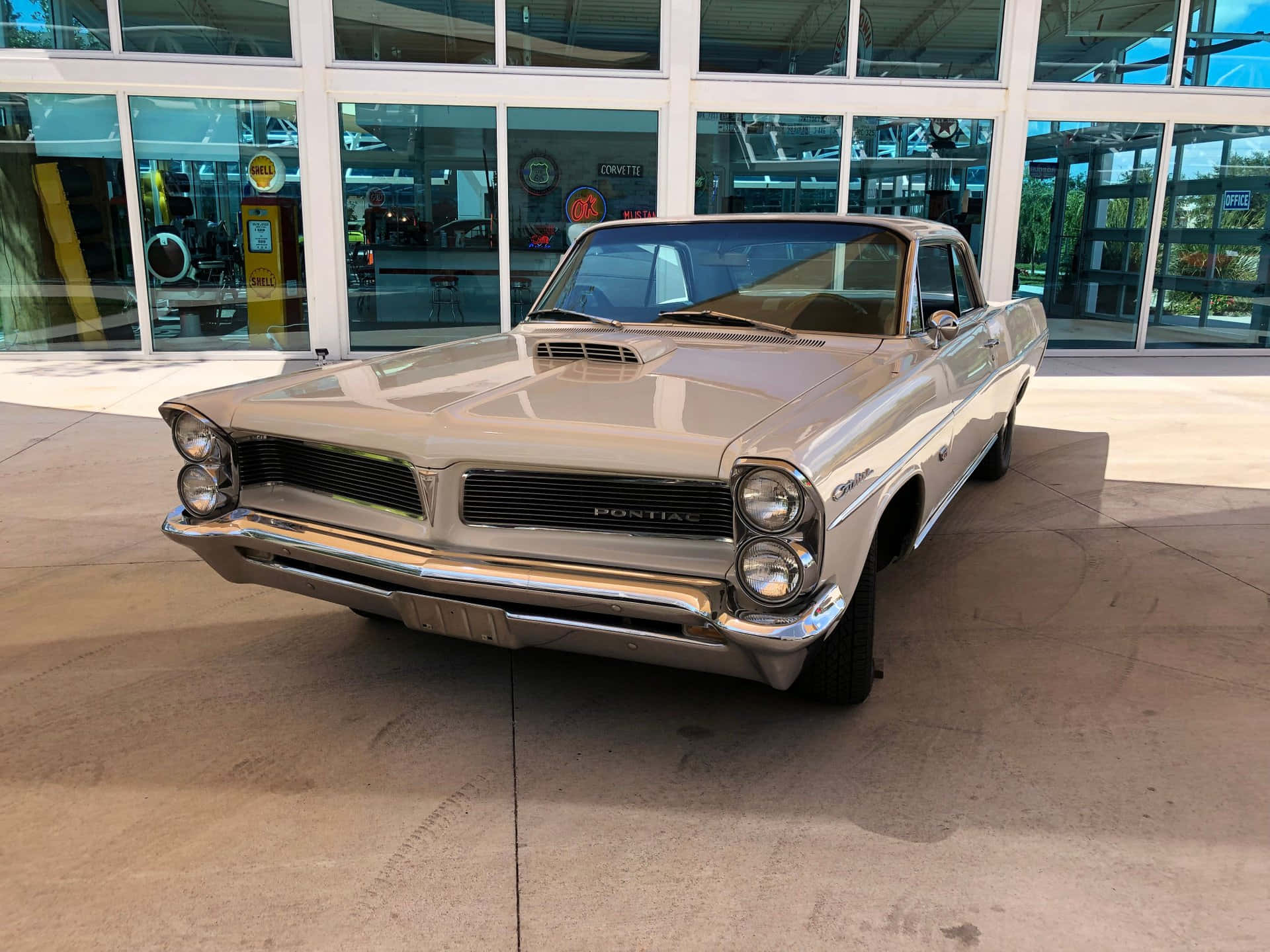 Pontiac Catalina 桌布 壁紙 — 一輛閃亮的銀色1960年代龐蒂亞克GTO經典肌肉車停放在現代玻璃建築下。