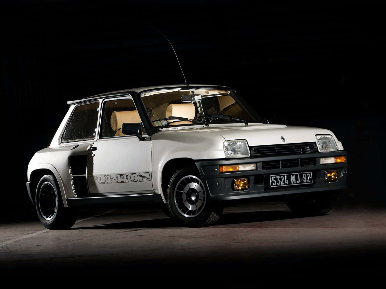Renault 5 Turbo 桌布 壁紙 — 一輛銀色雷諾5 Turbo 2跑車在黑色背景下被戲劇性地照亮，展示其標誌性設計和賽車條紋。