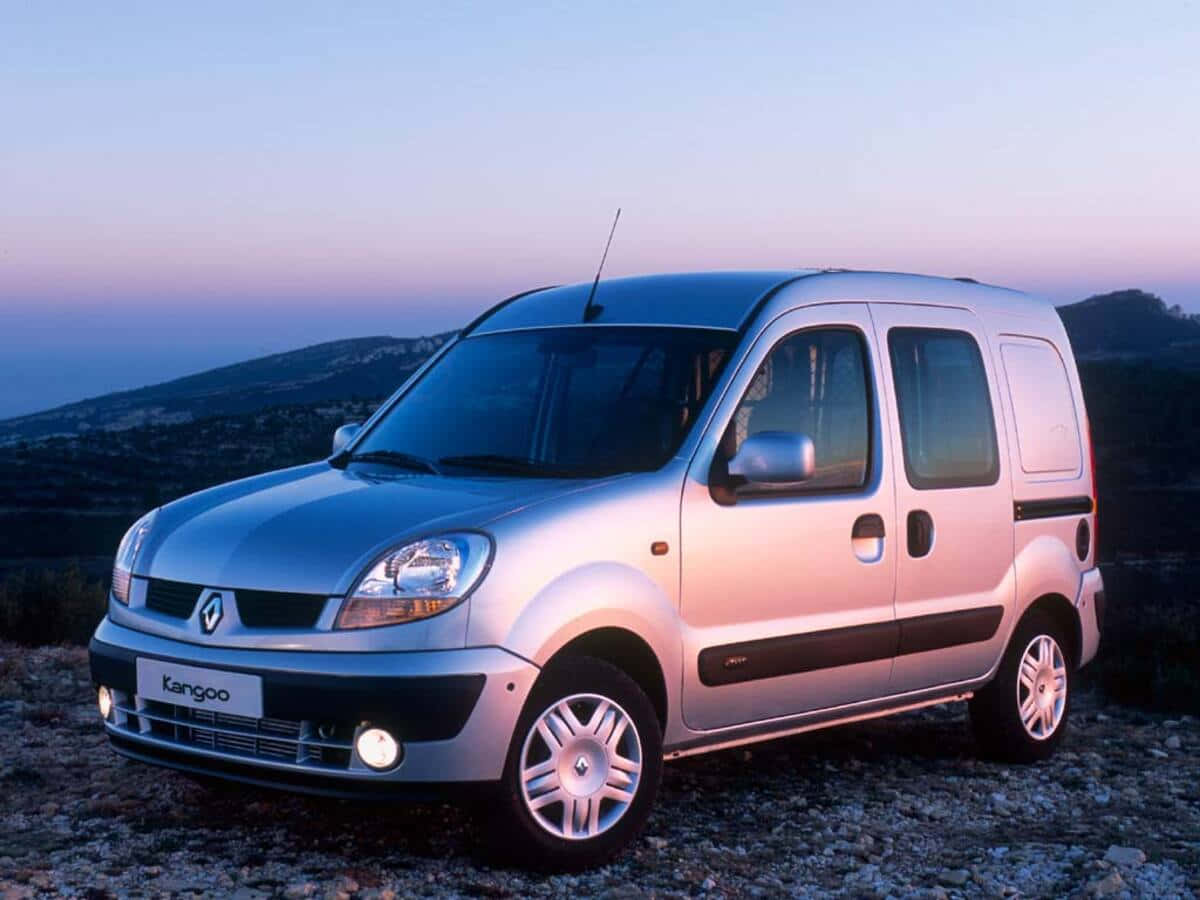 Renault Kangoo 桌布 壁紙 — 一輛銀色雷諾Kangoo客貨車停泊在岩石山坡上，暮色中背後是柔和的紫色和藍色天空。